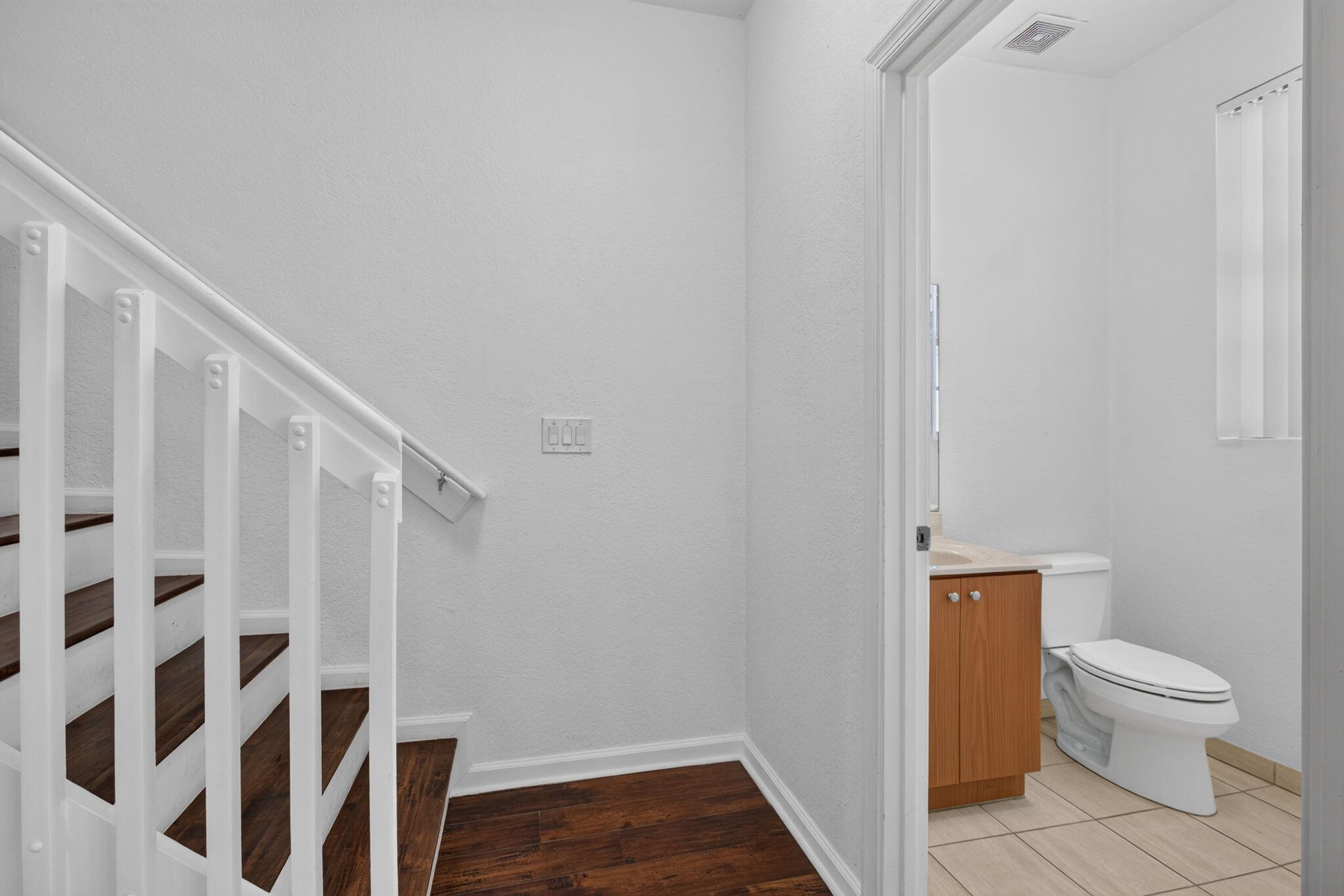 Wood-finish stairs with white risers and railing