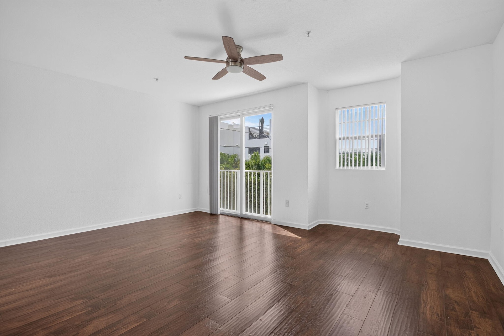 Hardwood-finish flooring, ceiling fan, sliding glass door with balcony access, and a window with blinds