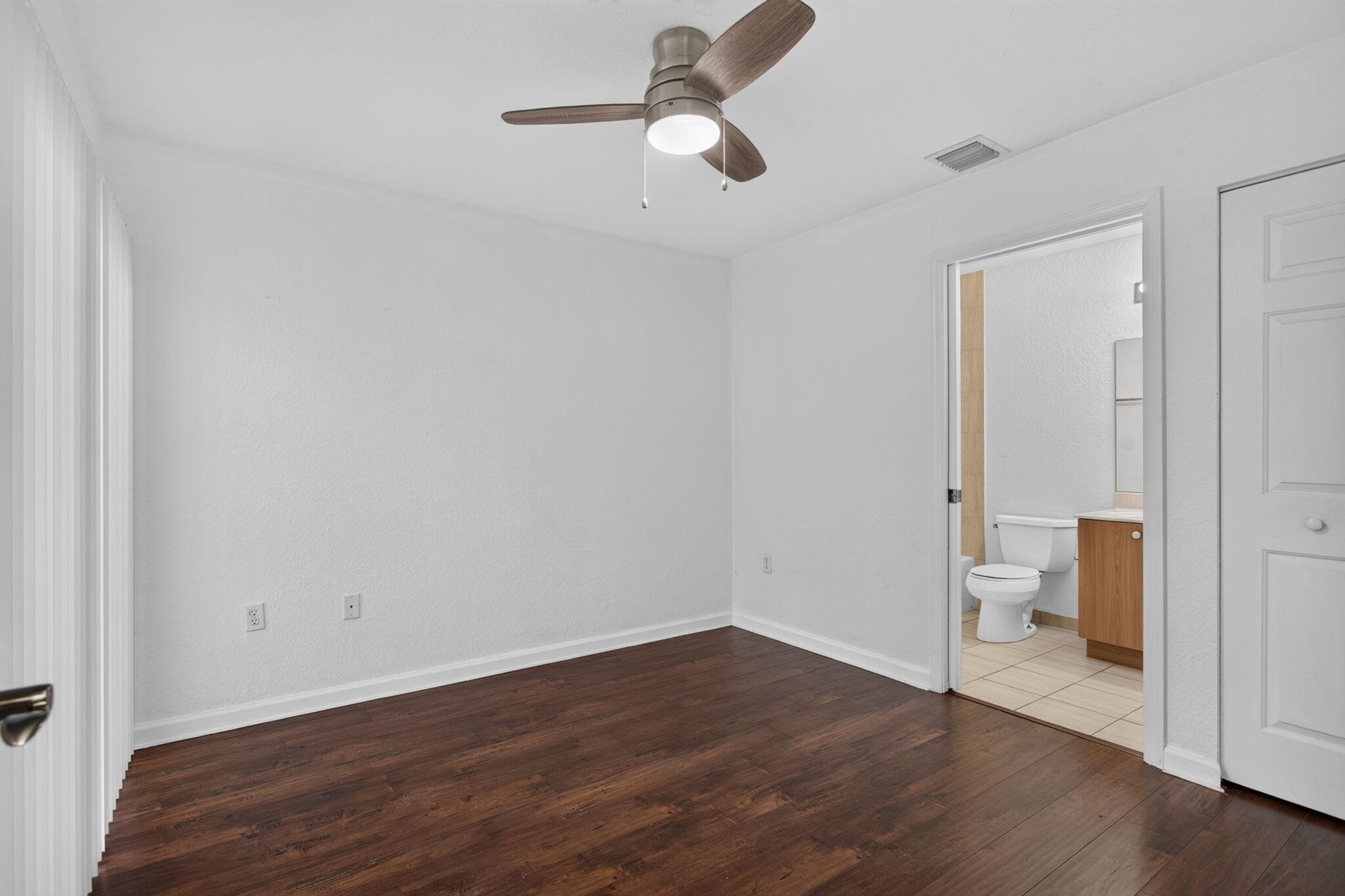Wood-finish flooring, ceiling fan, white wall paint, white trim, and a white paneled door