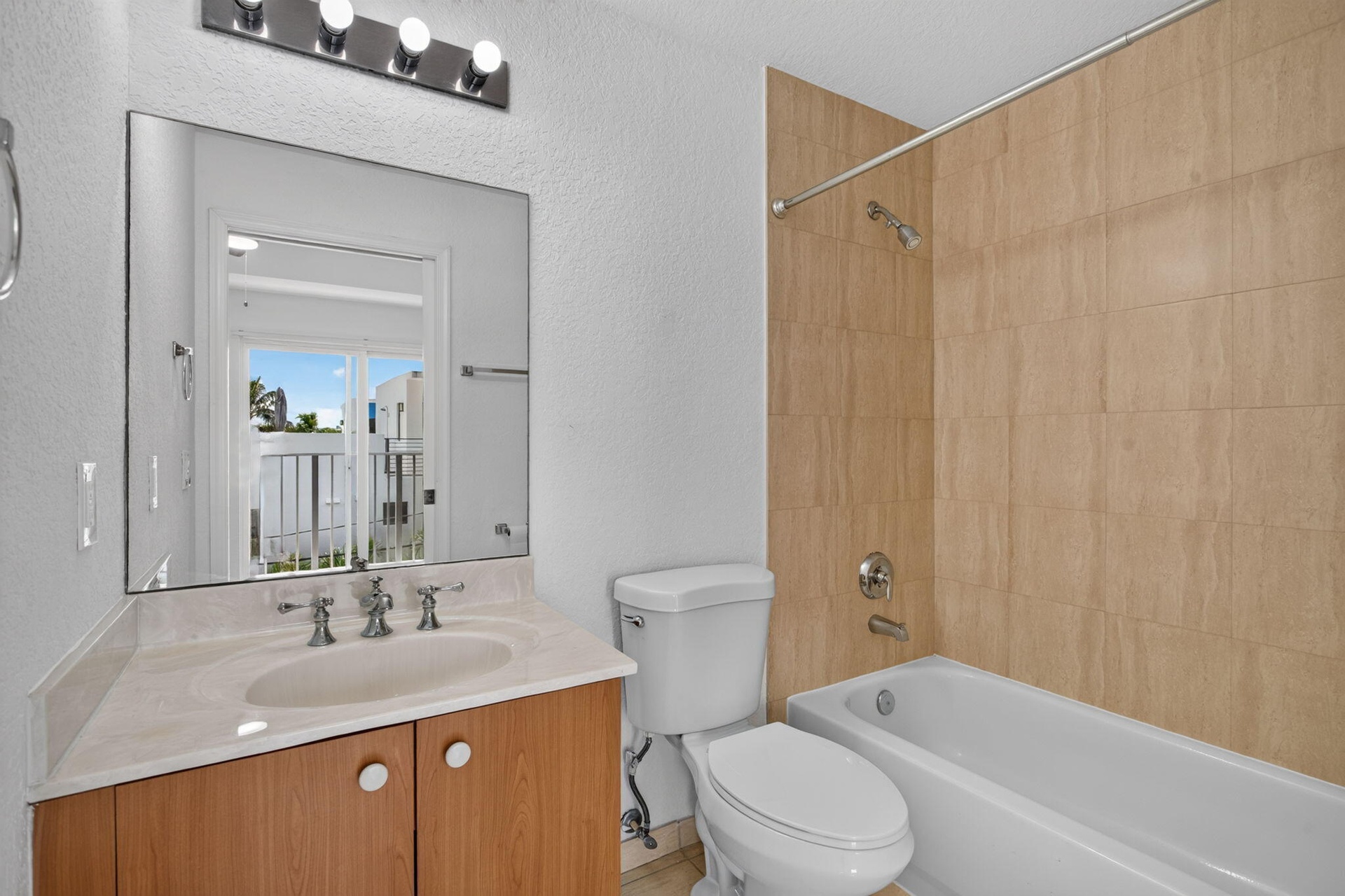 Bathroom featuring a vanity with a light-toned countertop, integrated sink, wood-finish cabinetry, and a full-width mirror