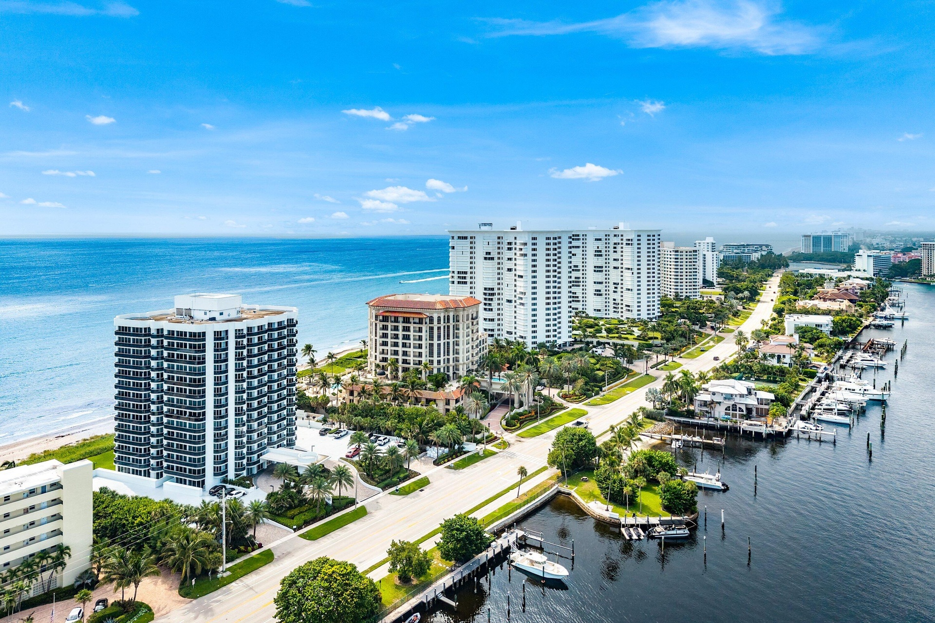 Coastal real estate featuring oceanfront buildings, waterfront properties with boat docks, and a wide sandy beach
