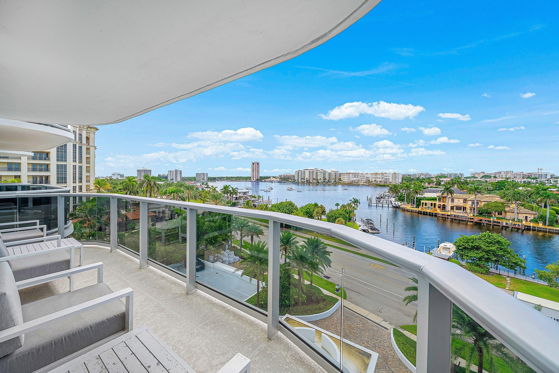 Expansive balcony featuring a glass railing, concrete flooring, and a curved ceiling