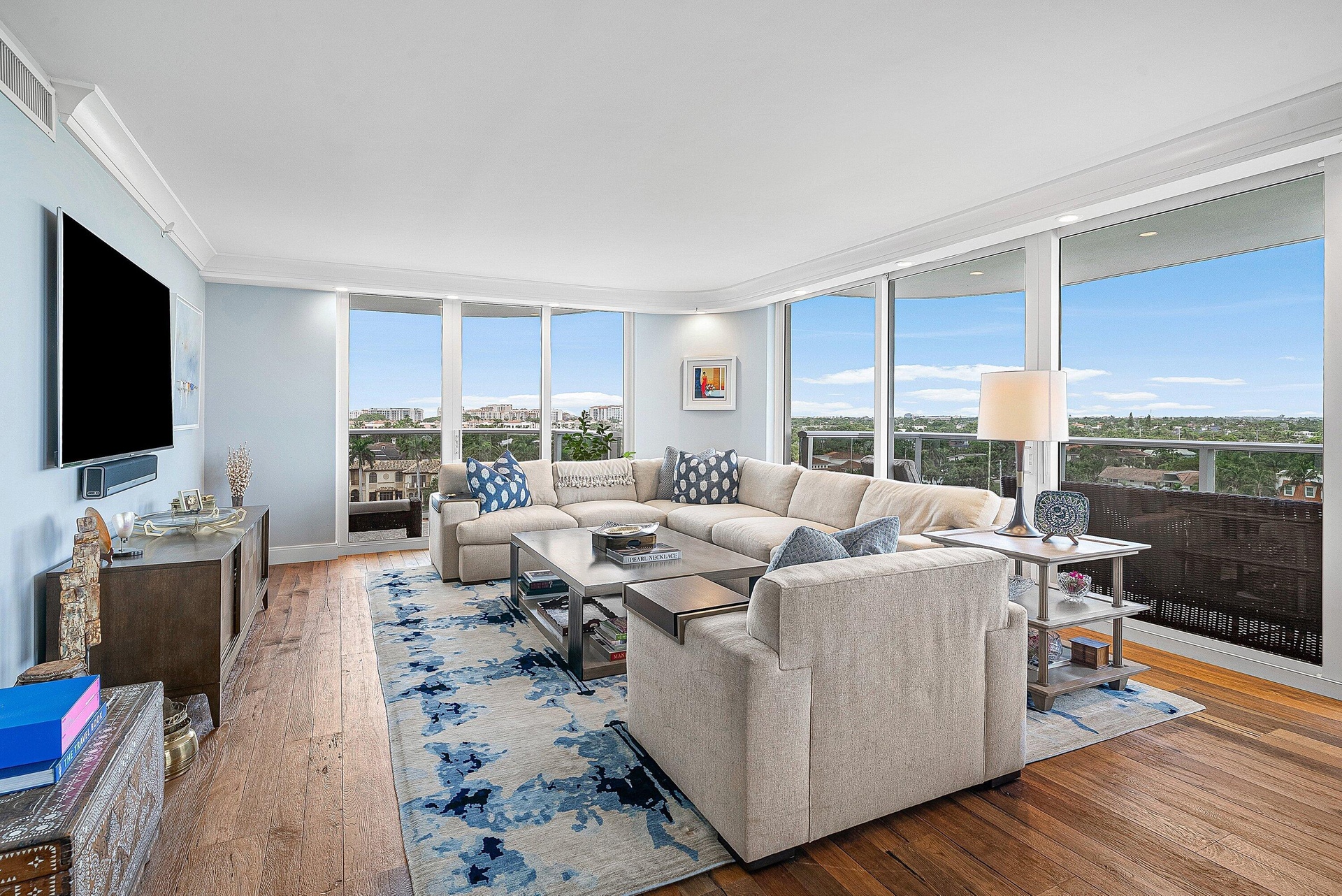 Expansive window wall with balcony access, wood-finish flooring, recessed lighting, and crown molding