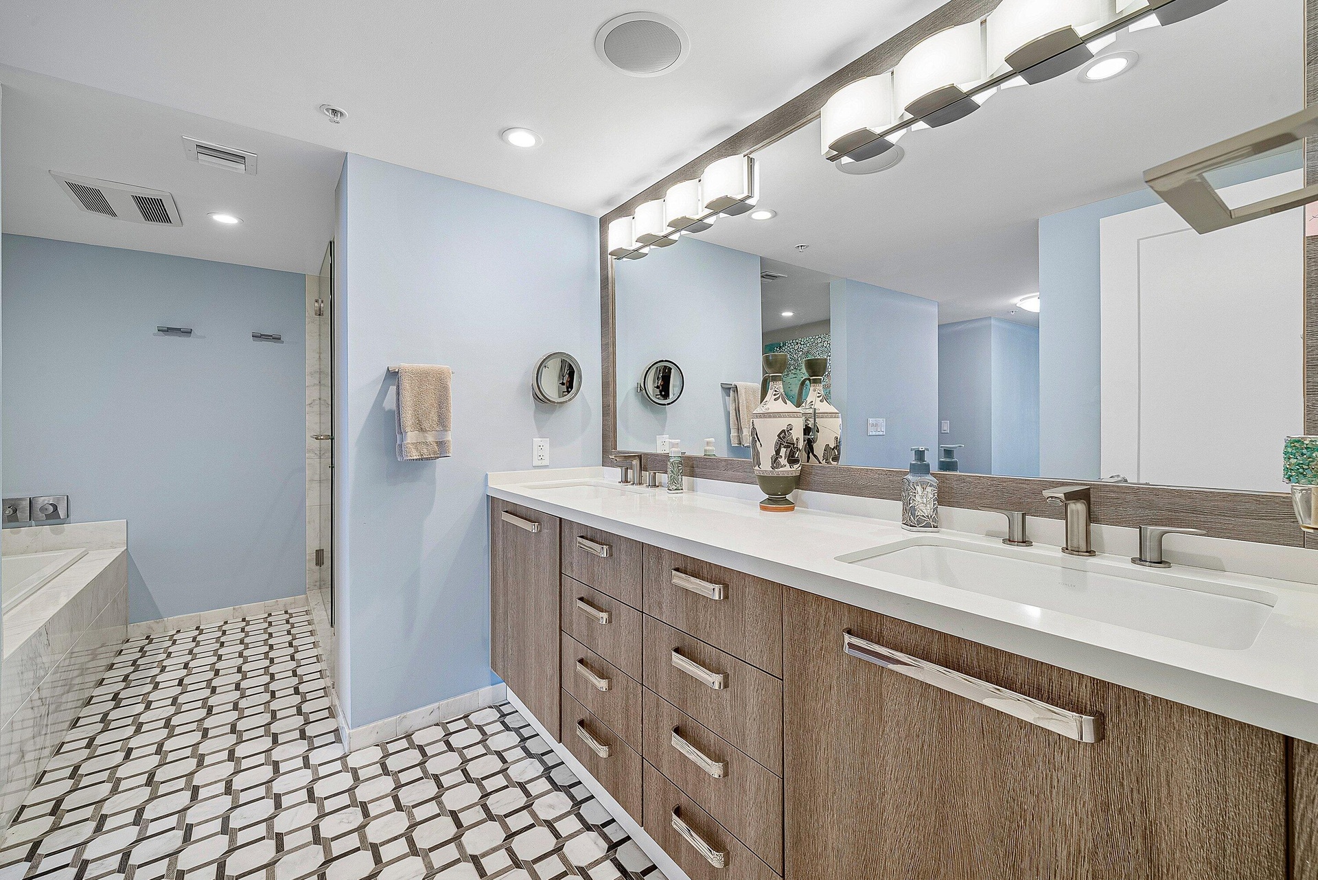 Dual vanity with white countertops, wood-finish cabinetry, and brushed nickel hardware