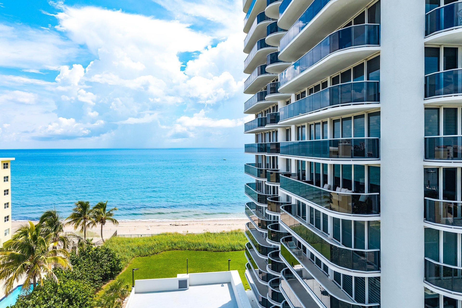 Oceanfront high-rise building with extensive balconies, glass railings, and a beachside location