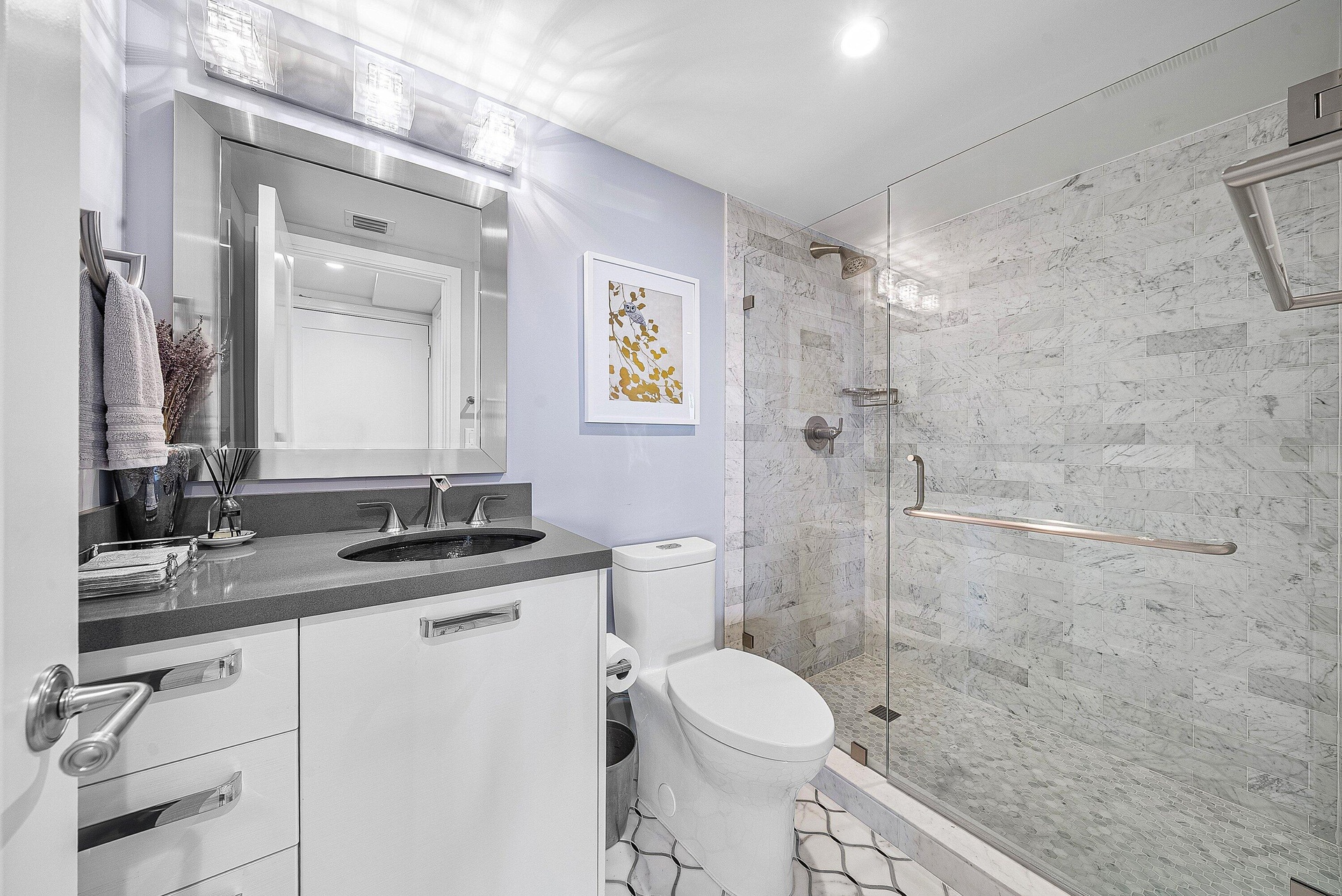 Modern bathroom featuring a single vanity with dark countertop, undermount sink, and a framed mirror