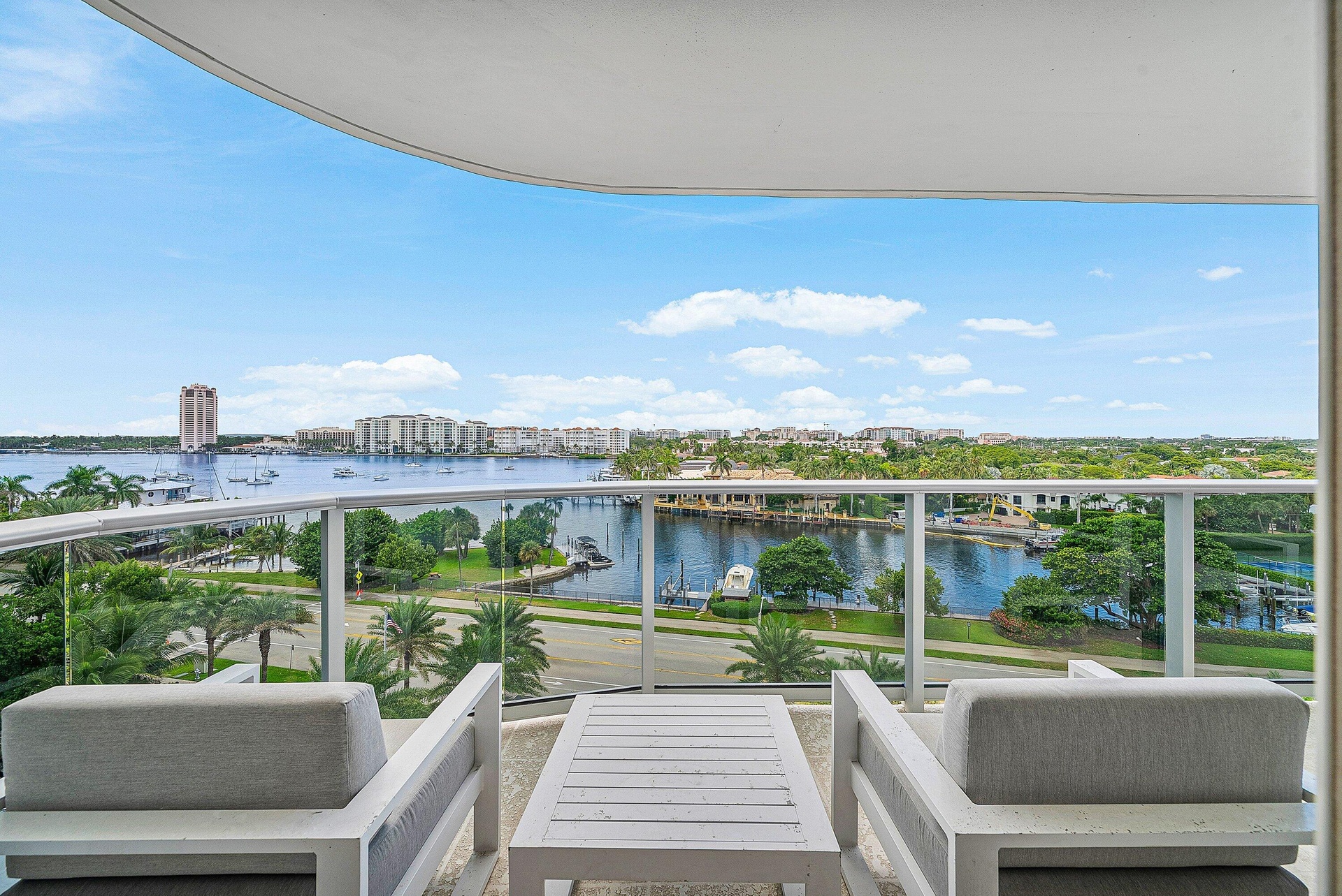 Expansive balcony featuring a glass railing, water frontage, and urban skyline