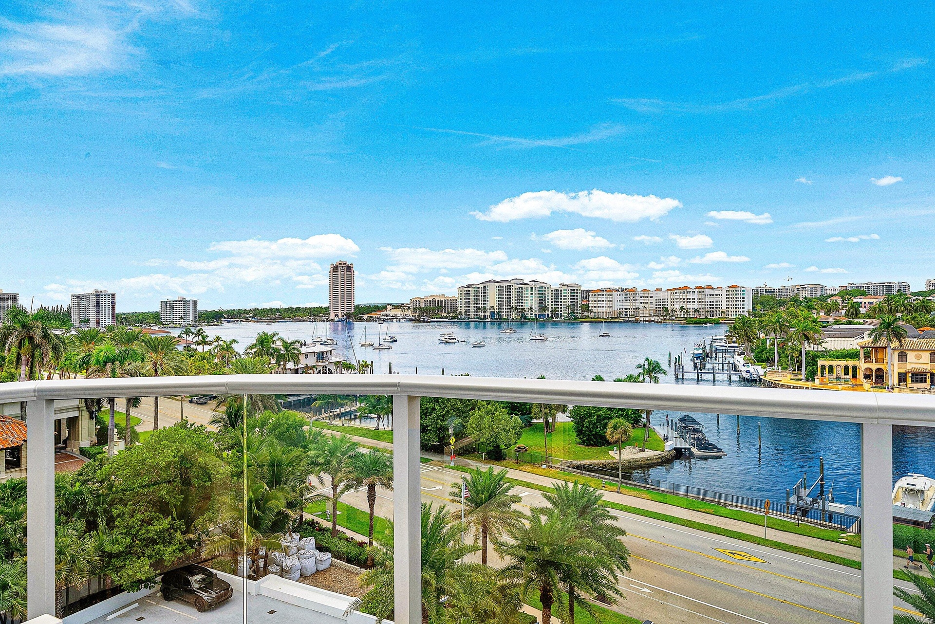 Waterfront scenery featuring a marina, multi-story buildings, and a clear glass balcony railing