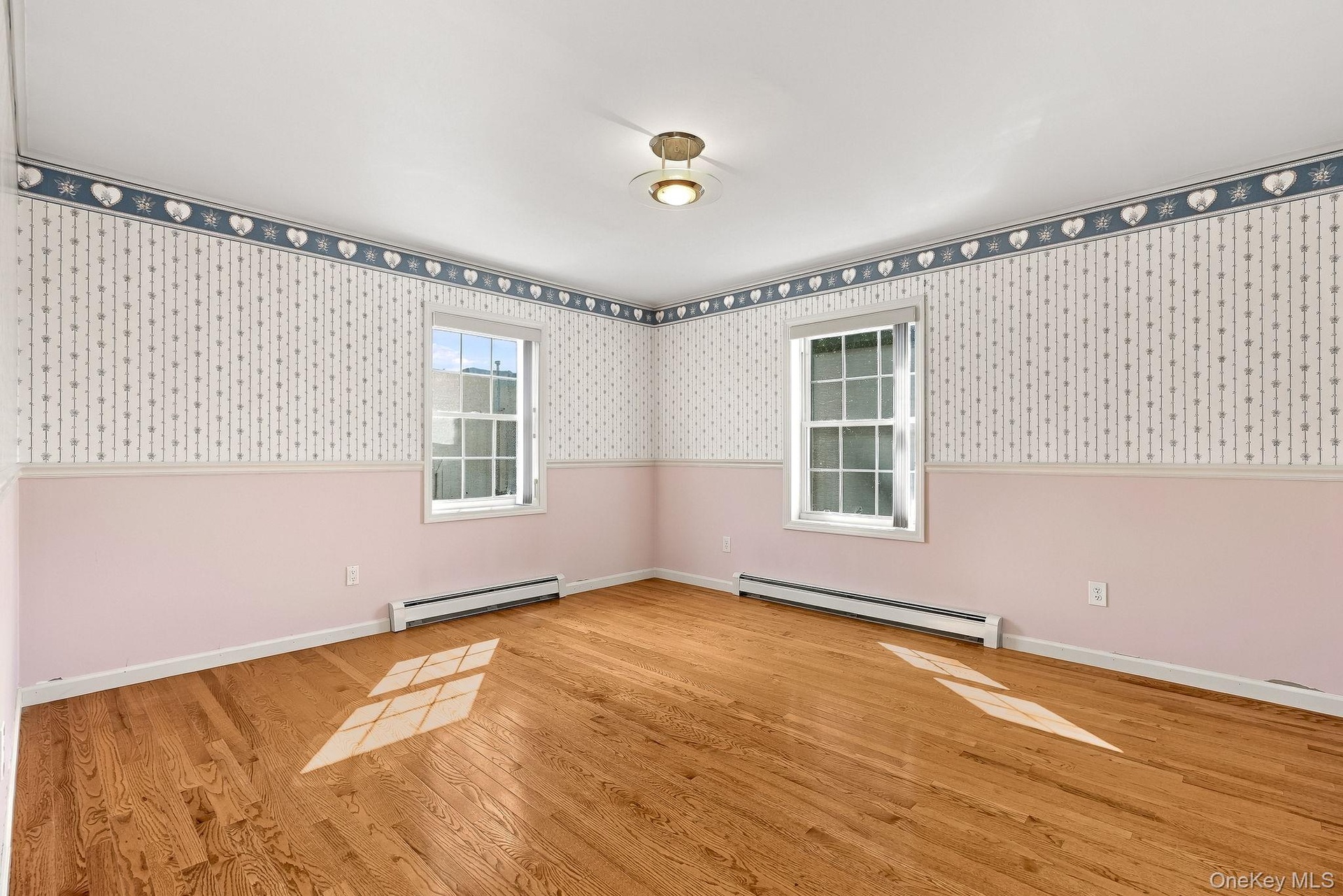 Bedroom four is at the end of the hall, to the back of the house and has windows on two sides of the space.