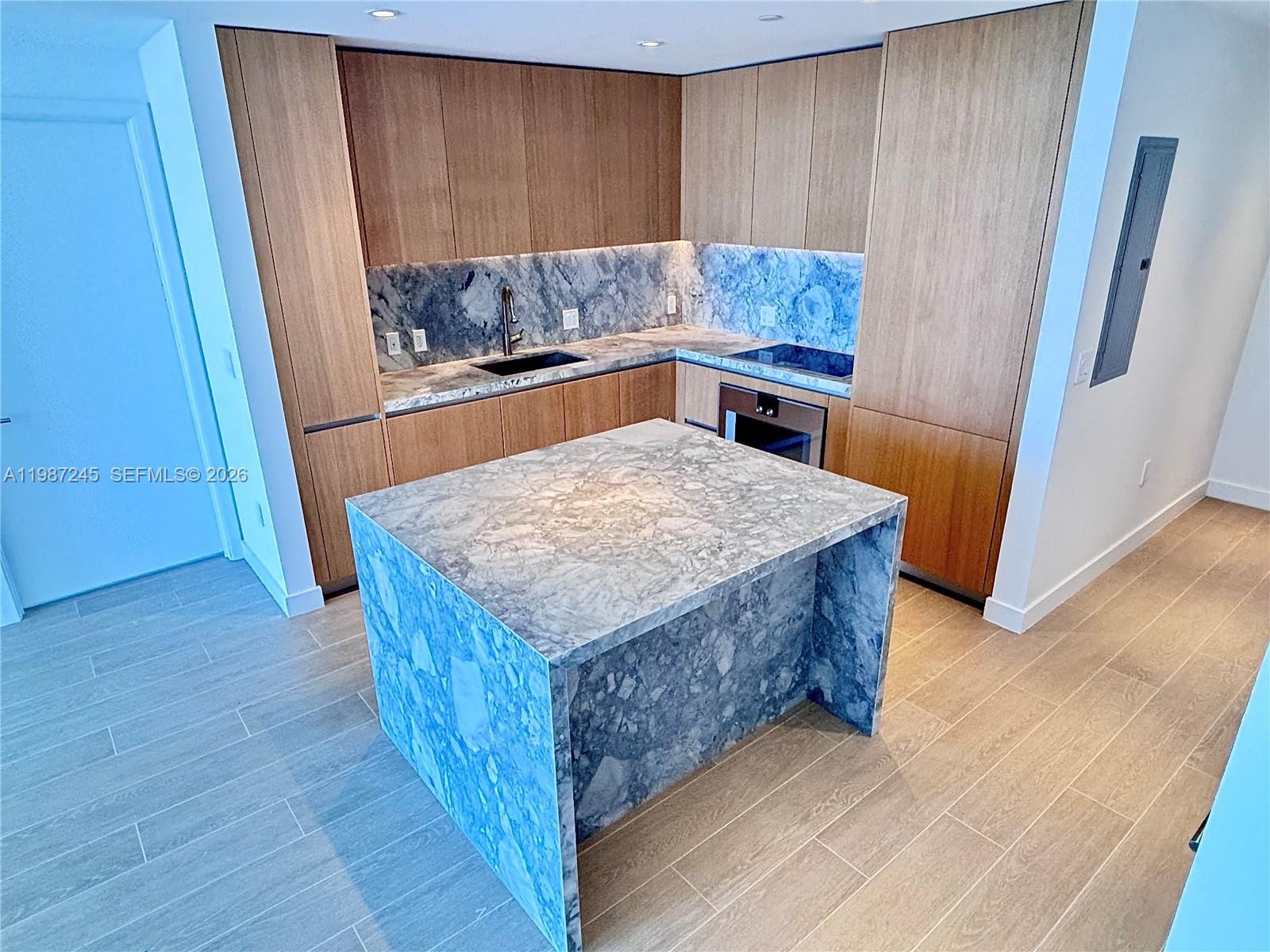 Kitchen with custom island with matching ItalKraft cabinetry and quartzite waterfall
