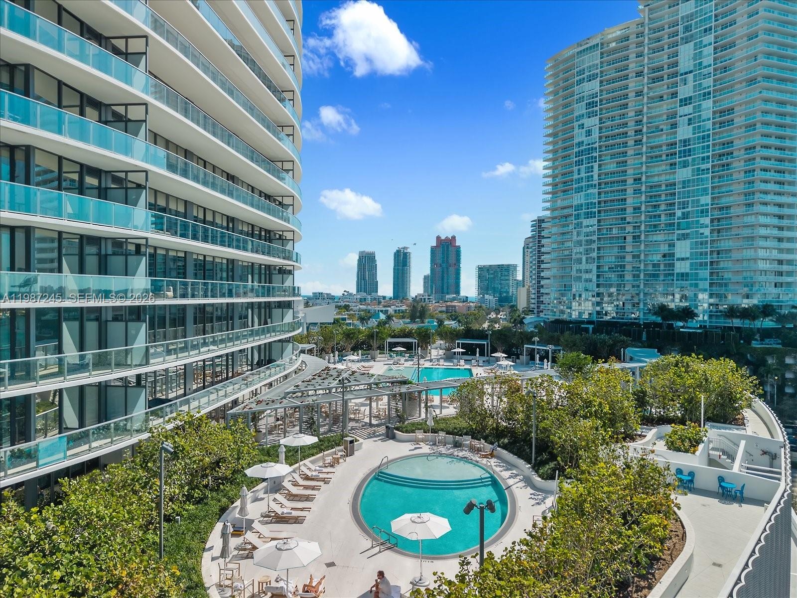 View of the outdoor amenity deck with multiple pools and full-service dining at Five Park Miami Beach