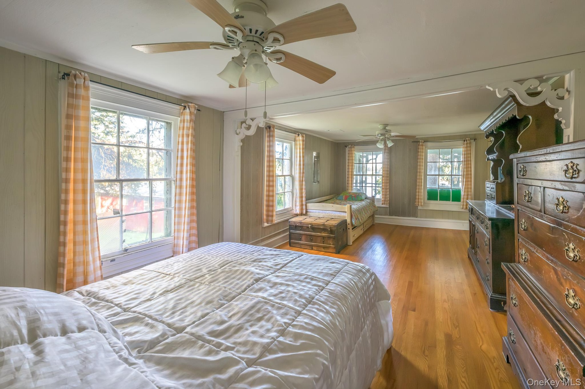 Hardwood flooring throughout, multiple windows, ceiling fans, and paneling
