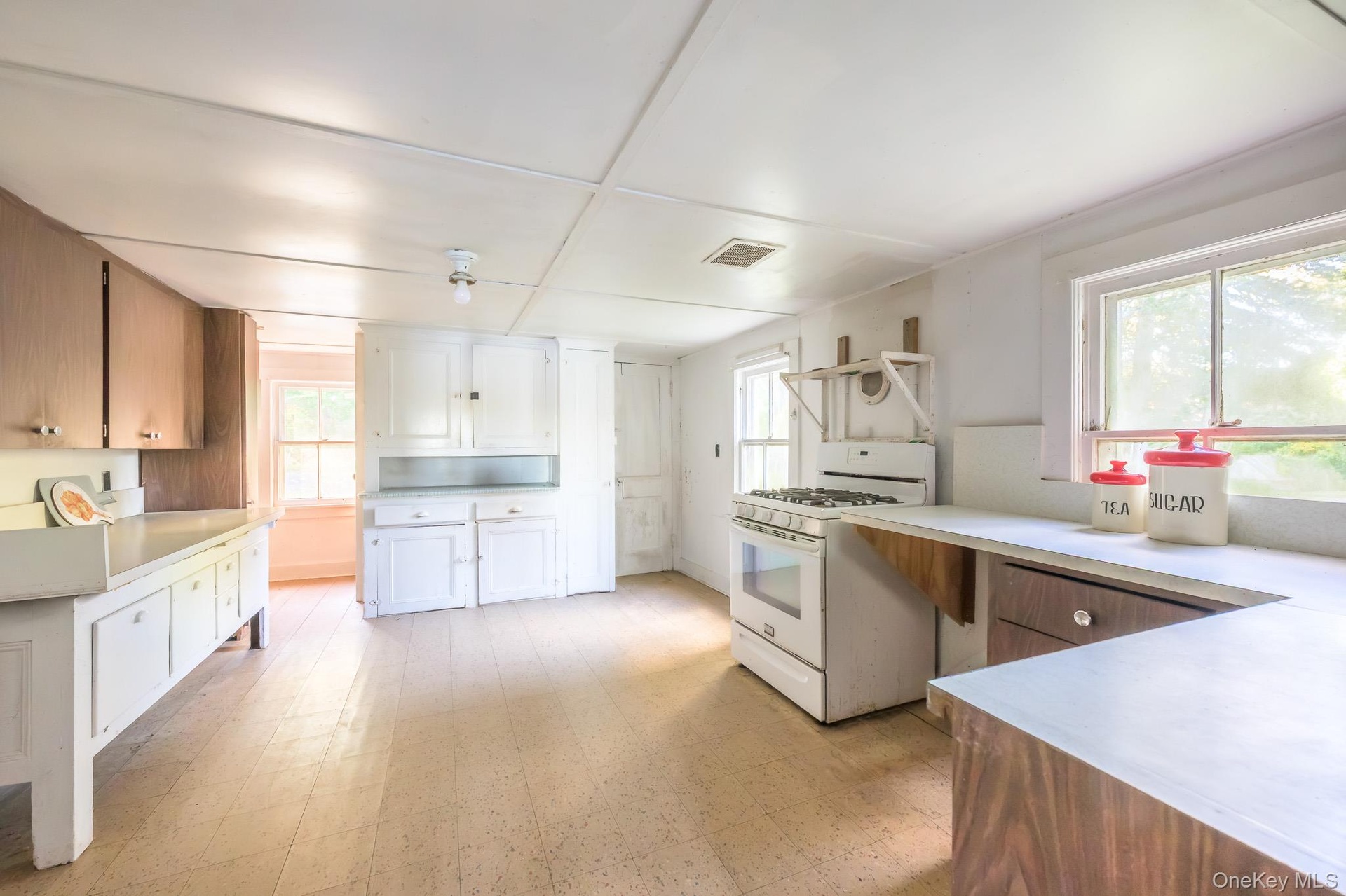Kitchen featuring wood-finish flooring, white cabinetry, a freestanding range, and a built-in sink
