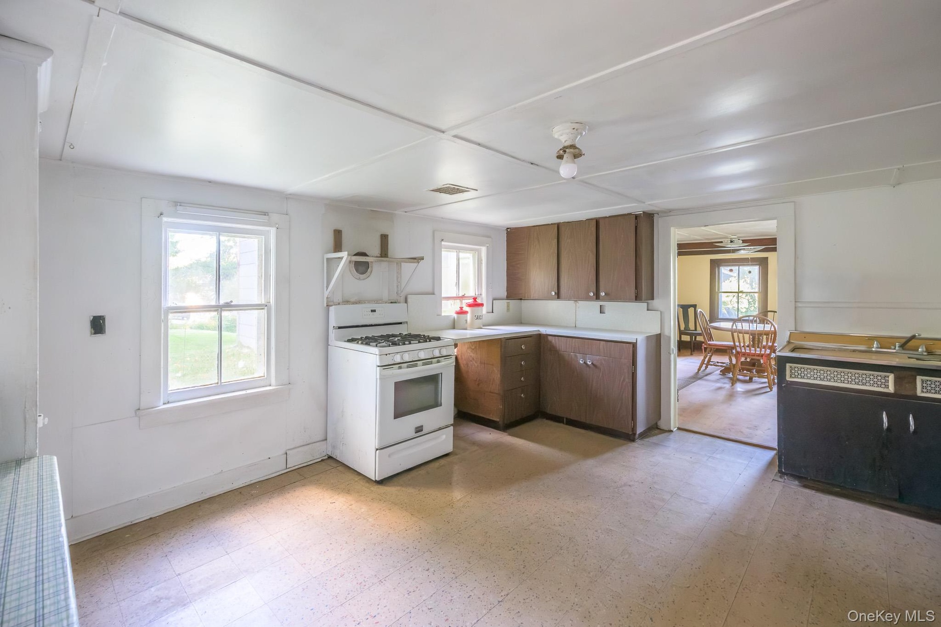 Kitchen area featuring wood-finish cabinetry, a gas range, and a window above the sink
