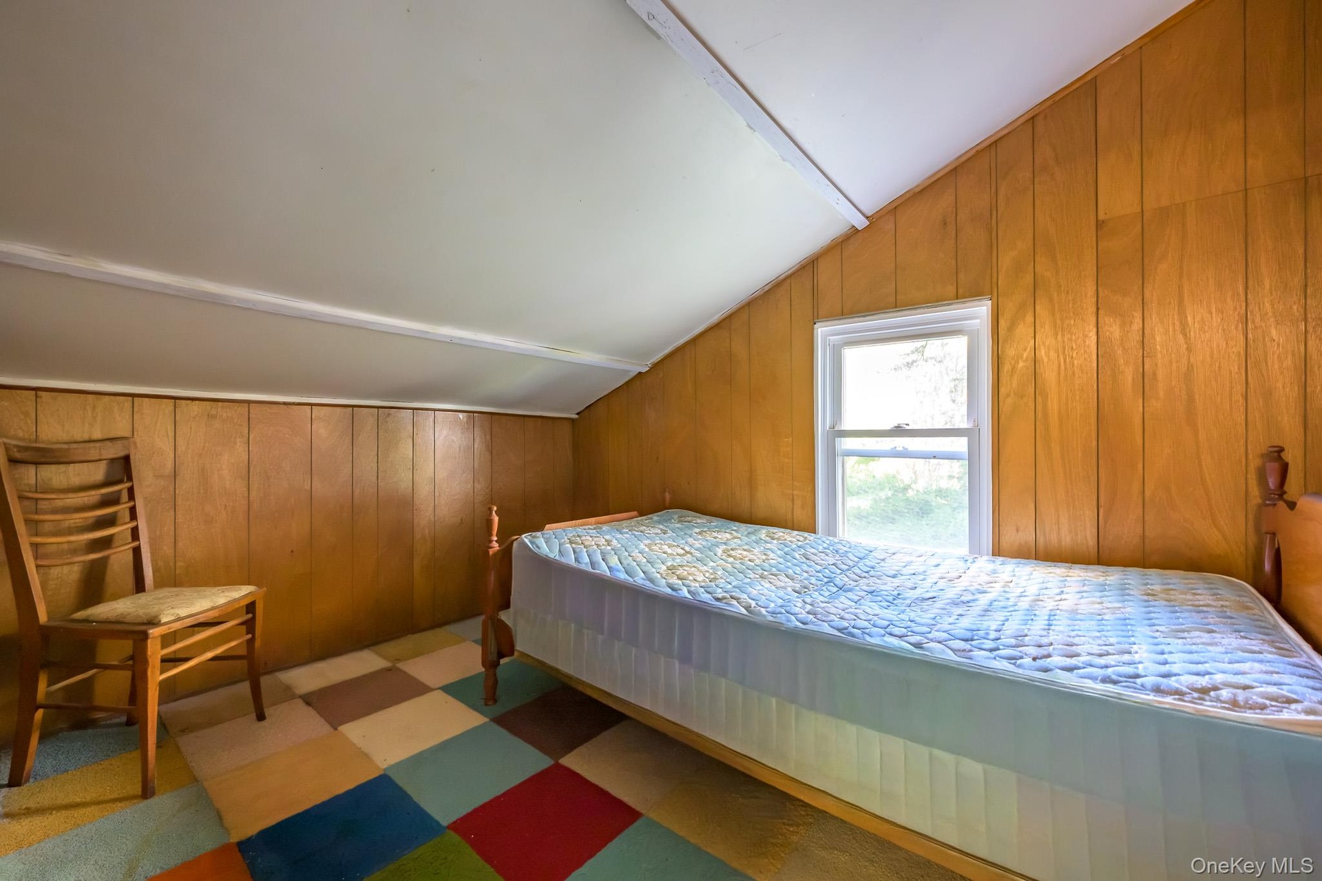 Sloped ceiling, wood paneling, white window frame, and checkered flooring