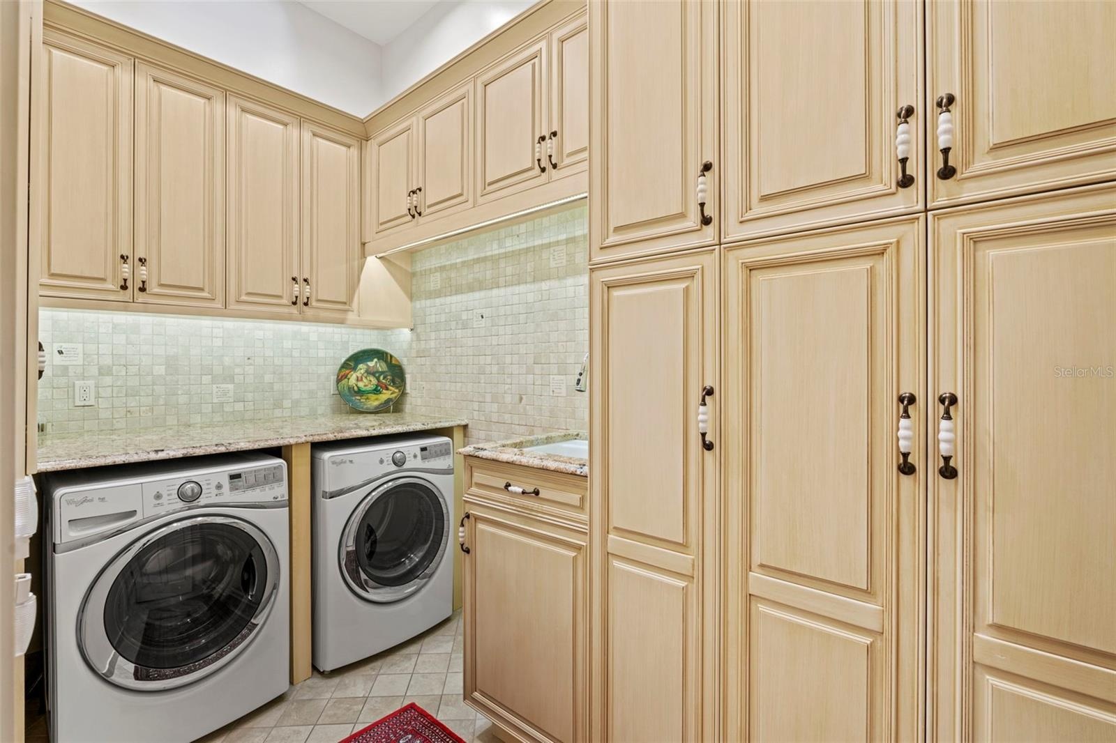 Laundry Room with sink and plenty of custom storage cabinets for cleaning supplies and paper goods.