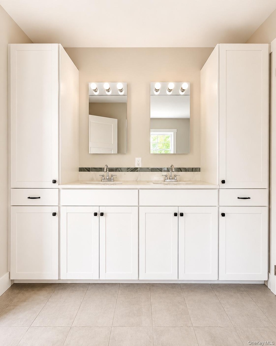 Double vanity with white cabinetry and dark hardware