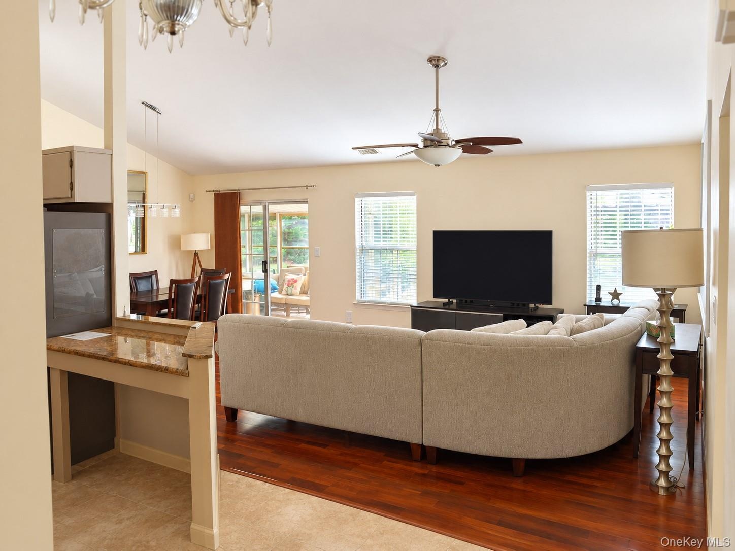 Hardwood-finish flooring, recessed lighting, ceiling fan, sliding glass door, and granite-finish countertop on a built-in desk