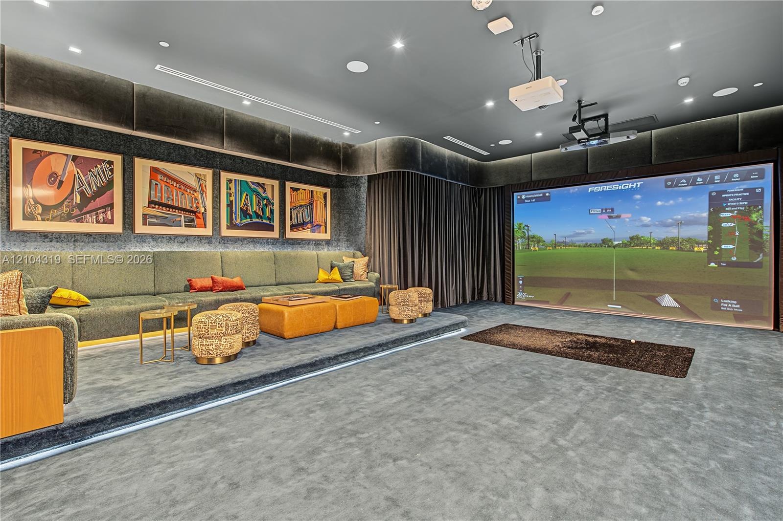 Media room featuring tiered flooring, custom upholstered wall panels, recessed lighting, and a built-in projection system with a golf simulator screen