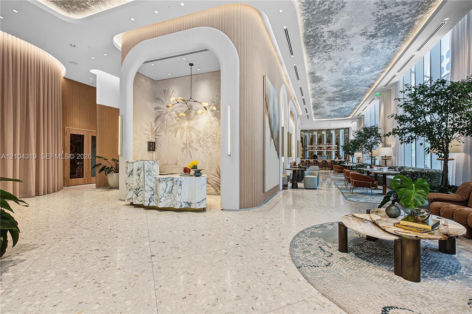 Open lobby featuring terrazzo flooring, fluted wood paneling, arched architectural detailing, a stone-cladding reception desk, and a decorative coffer