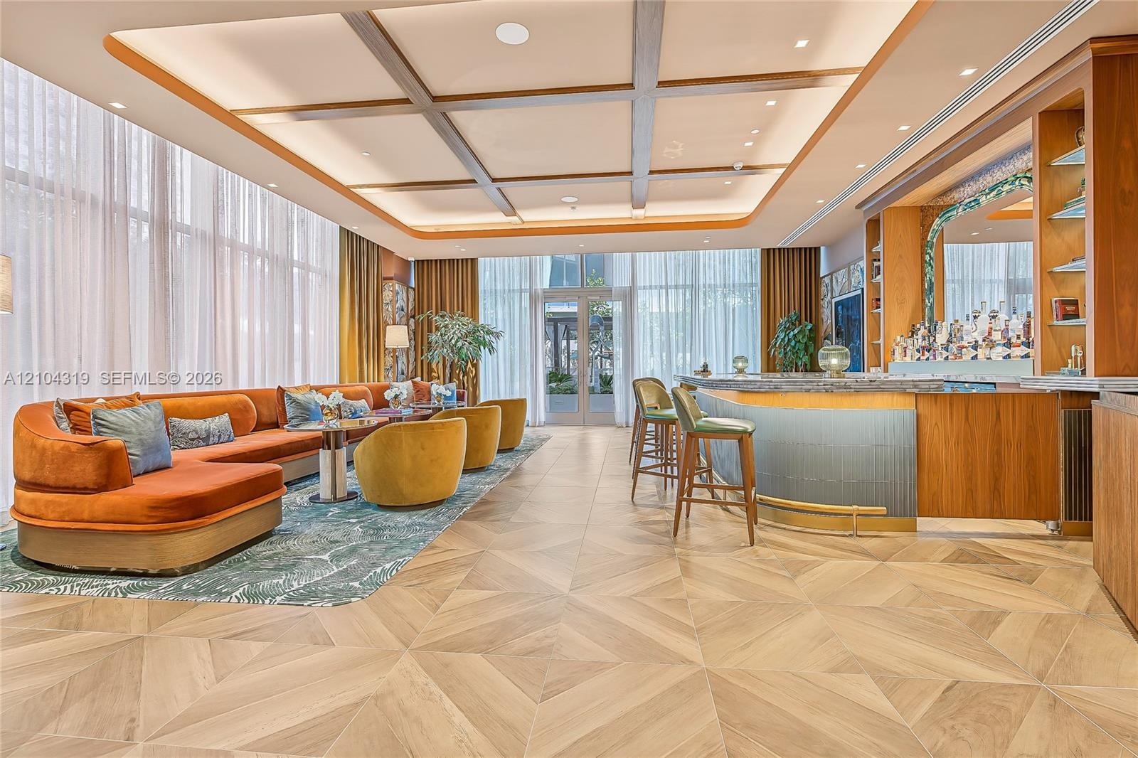 Coffered ceiling with recessed lighting, full-height windows, wood-finish geometric flooring, and custom built-in bar with stone-surfaced counter and 