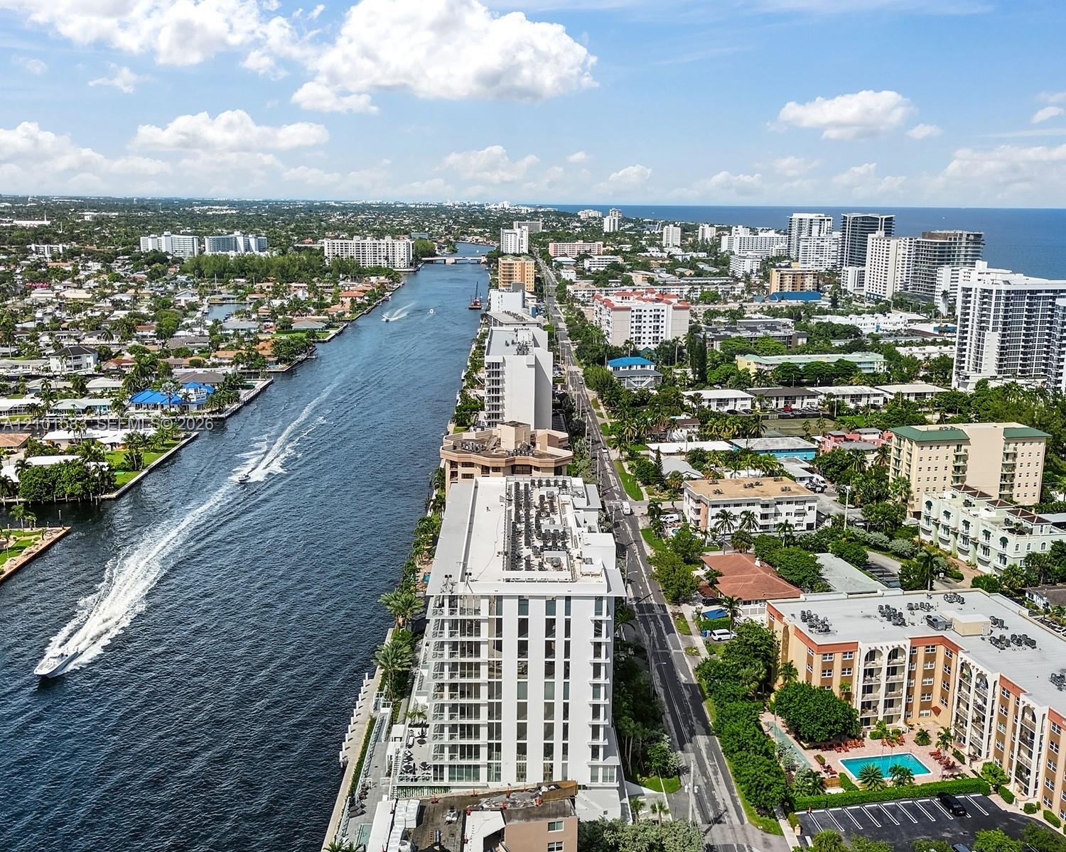 Aerial perspective featuring expansive waterway frontage, multi-story coastal structures, and mature palm tree landscaping