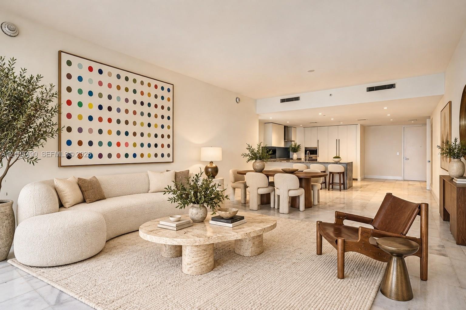 Open-concept interior featuring light-toned stone flooring, high ceilings with recessed lighting, and a modern kitchen with cabinetry and a center isl