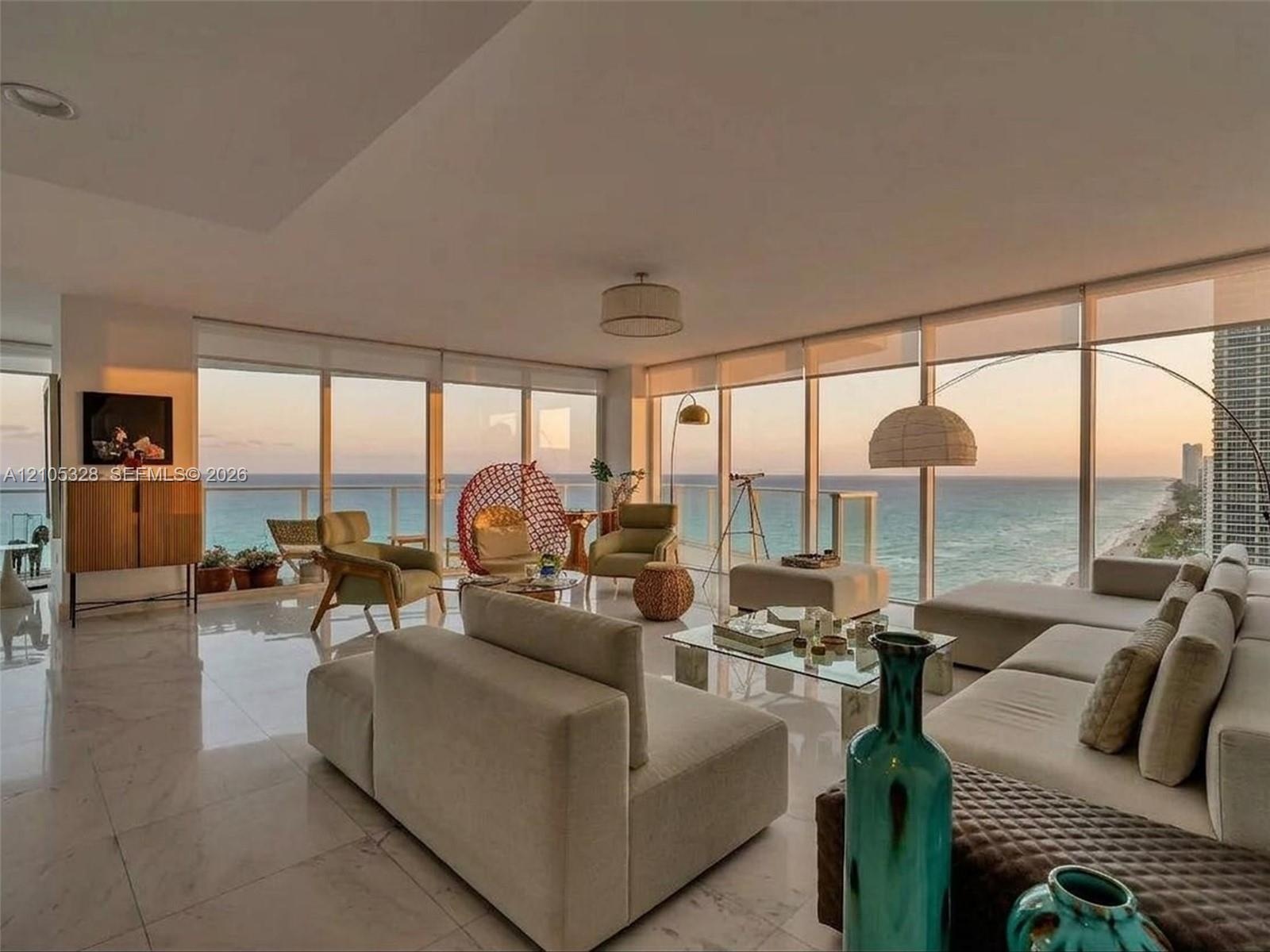 Expansive living area featuring floor-to-ceiling windows, panoramic ocean views, polished marble flooring, and recessed ceiling lighting.