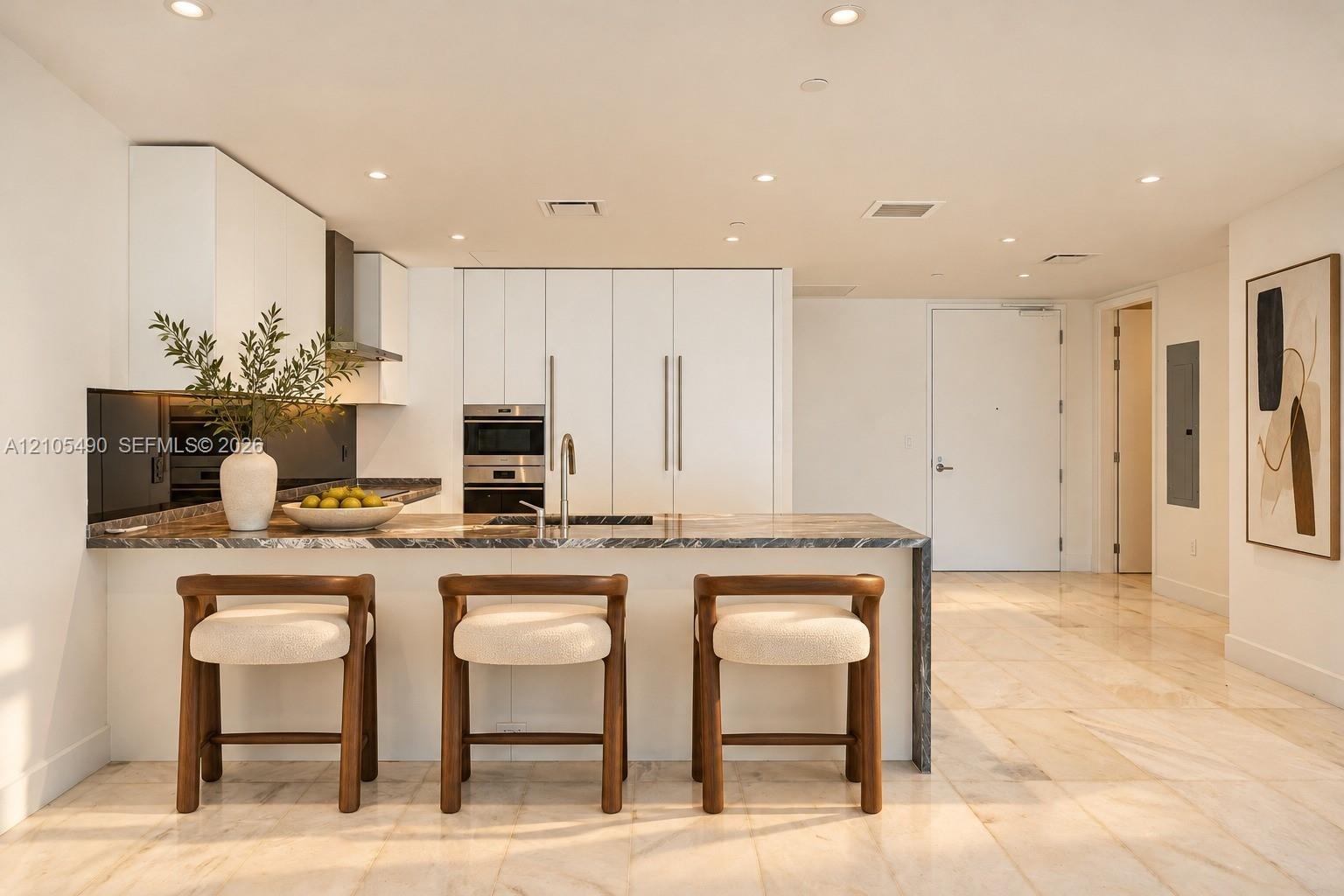 Modern kitchen featuring flat-panel cabinetry, stone countertops, integrated stainless steel appliances, recessed lighting, and large-format tile floo