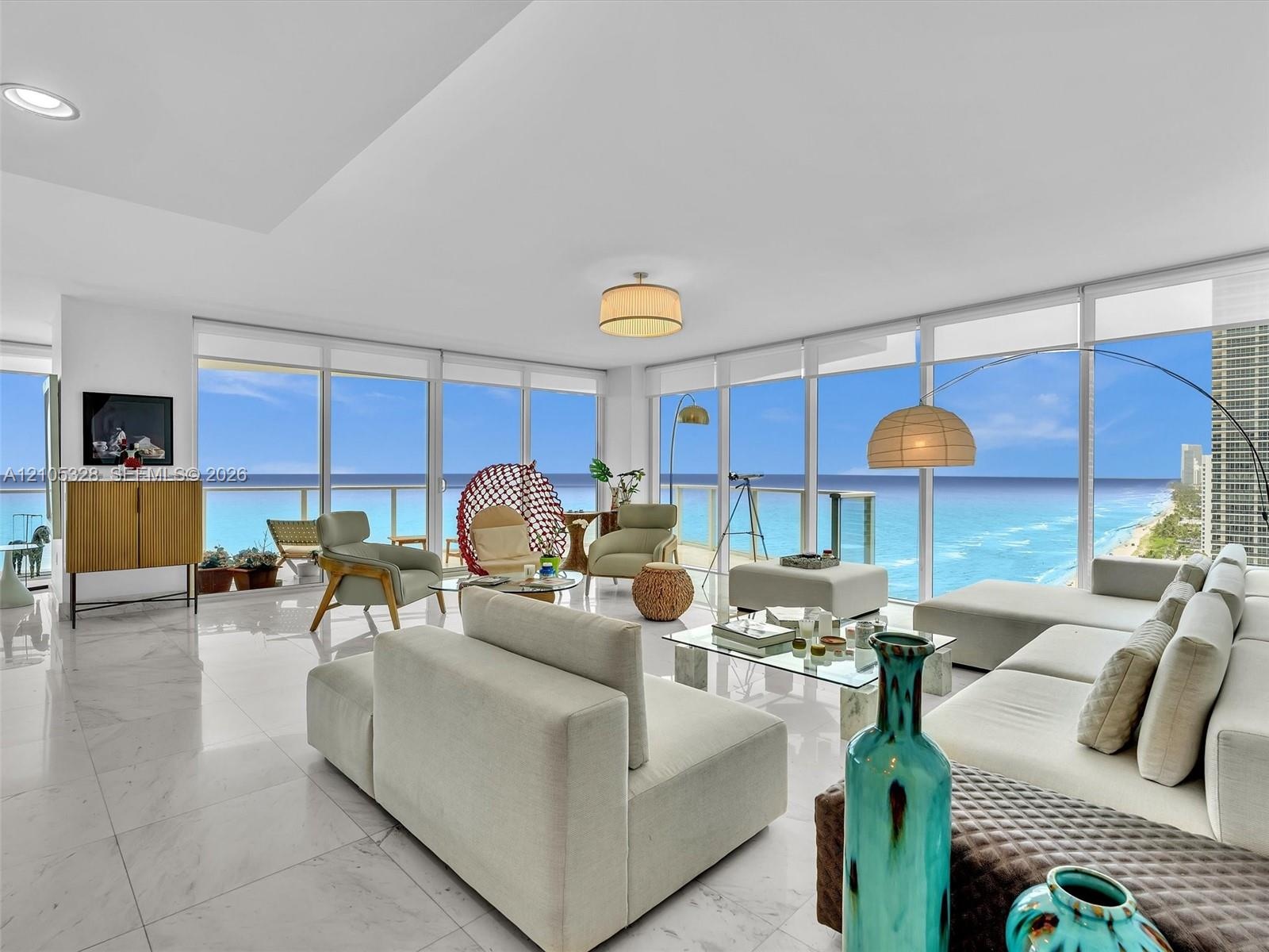 Elegant living area featuring Carrara marble flooring, floor-to-ceiling windows, stunning ocean views, and recessed ceiling lighting.
