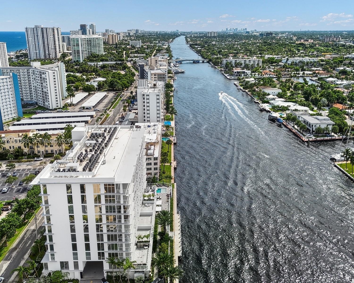 Waterfront high-rise building featuring a multi-story glass facade, dedicated ground-level swimming pool, and direct canal frontage