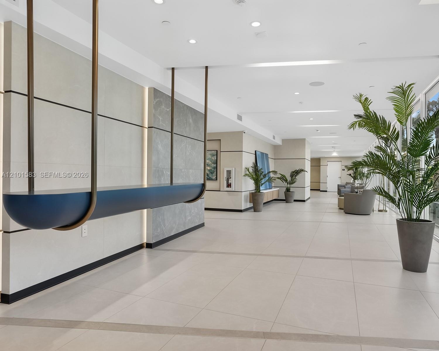 Common area featuring large-format tile flooring, recessed ceiling lighting, and walls accented with stone paneling and integrated vertical lighting