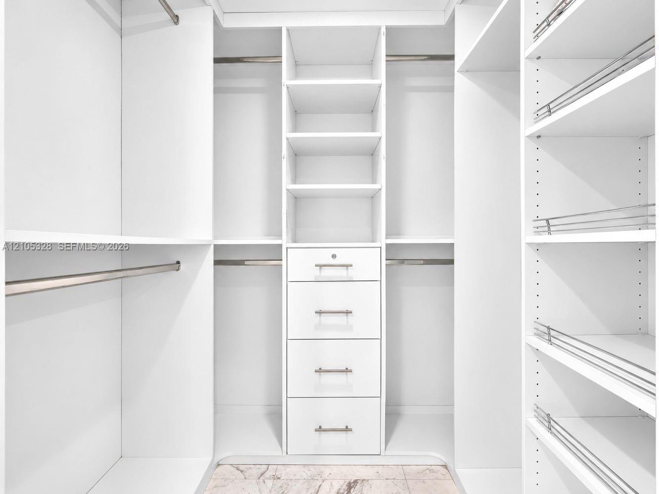 Custom-designed closet featuring ample hanging space, built-in shelving, and a five-drawer storage unit with brushed nickel hardware.
