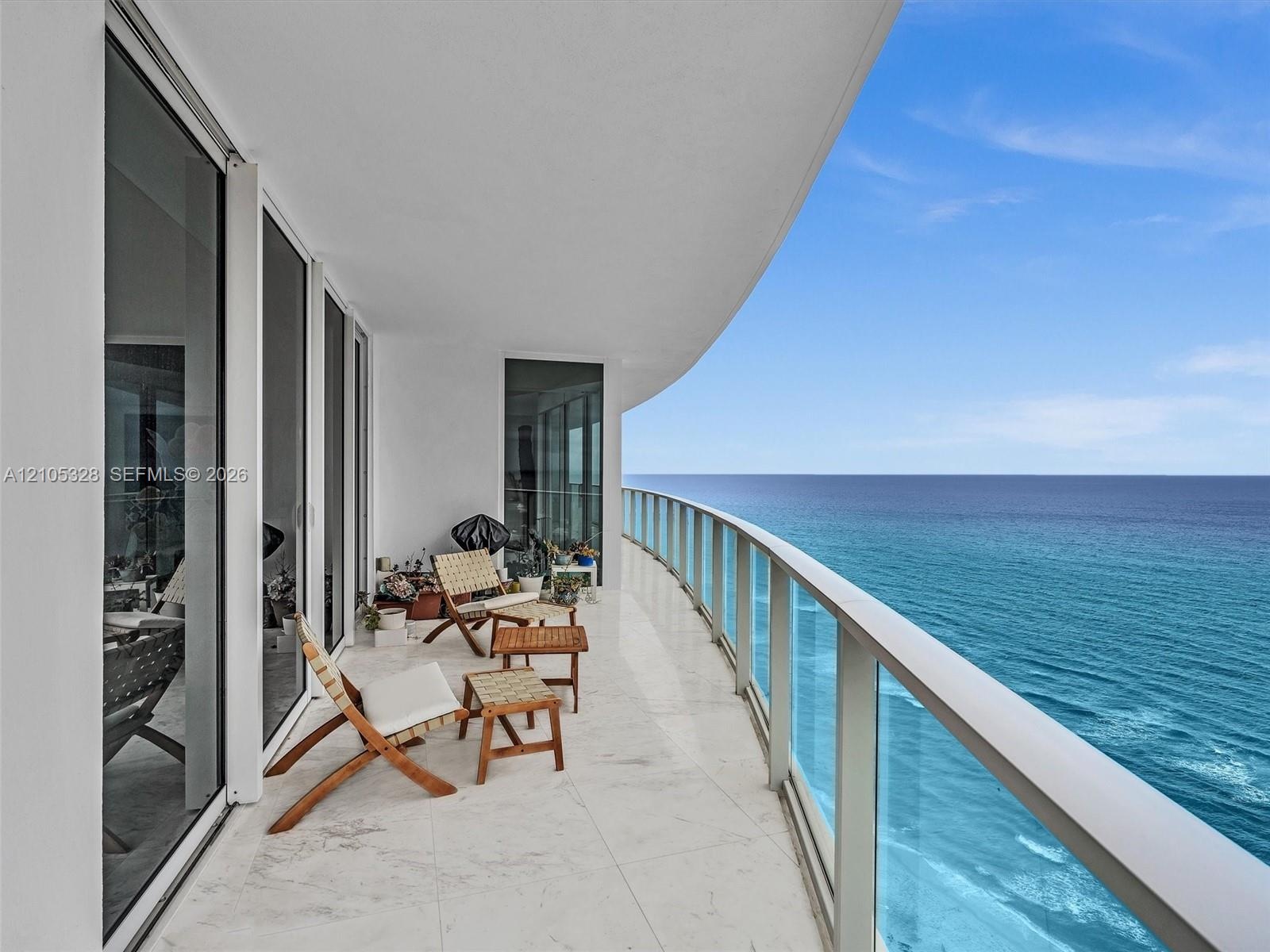 Expansive curved balcony with glass railings and panoramic ocean views.