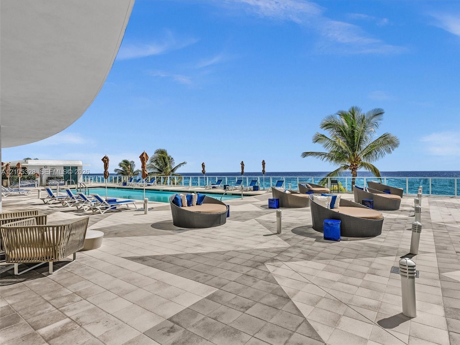Experience oceanfront resort-style living at Apogee Beach, featuring an inviting swimming pool, expansive pool deck, sleek glass railings, and direct 