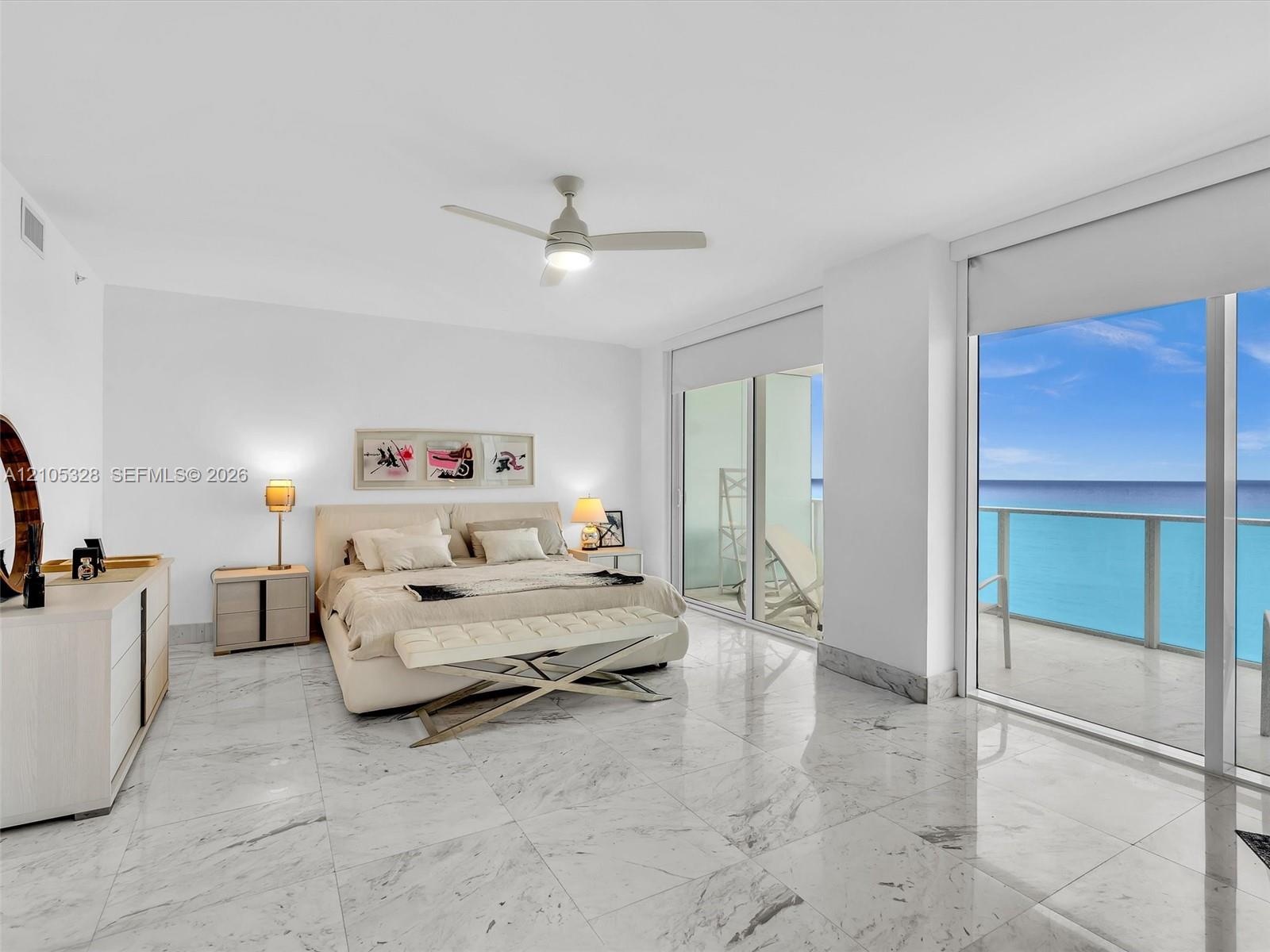 Sliding glass doors opening to a balcony, ceiling fan, white tile flooring, white walls, and a recessed ceiling