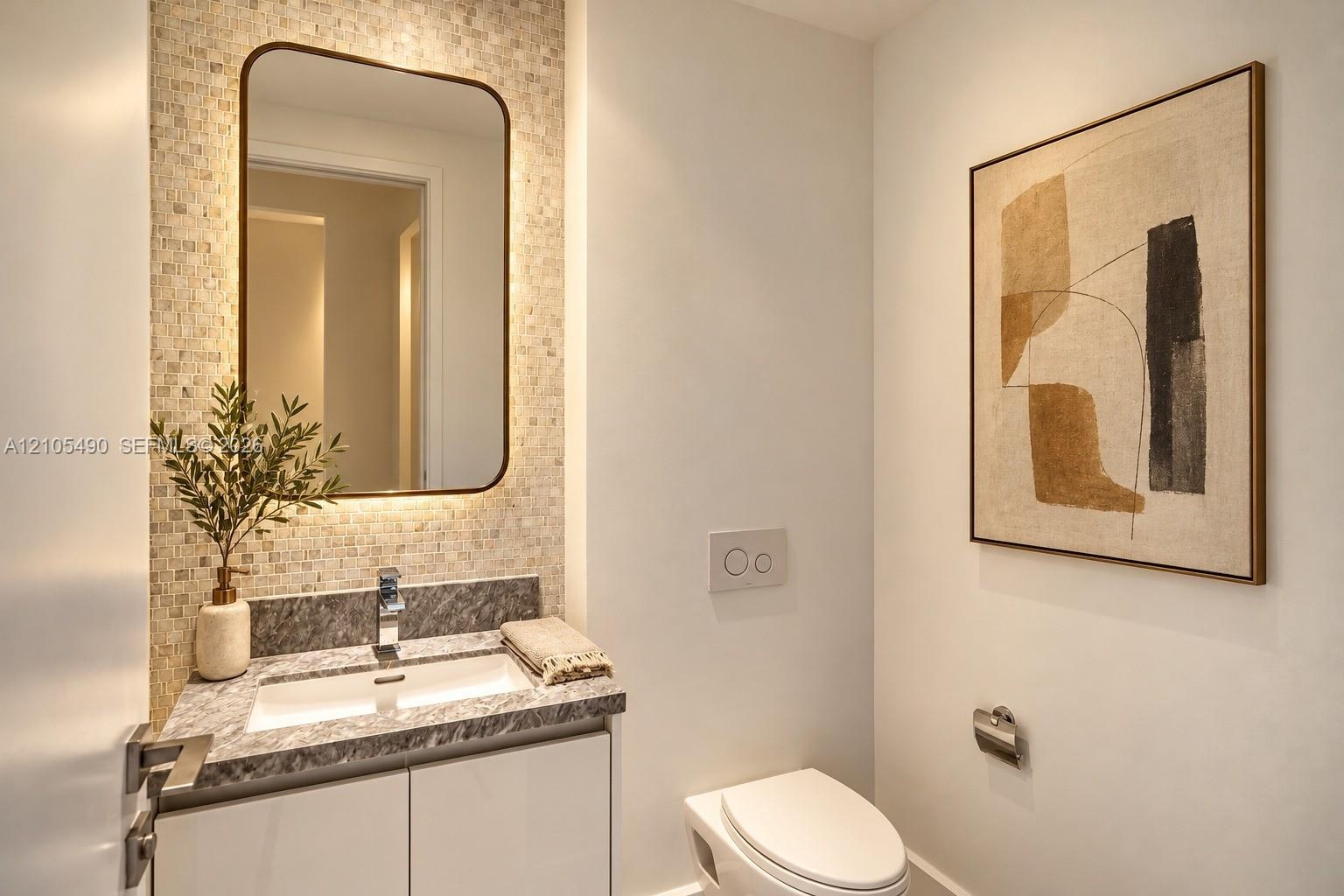 Floating vanity with a stone countertop, under-mount rectangular sink, mosaic tile backsplash, integrated mirror, and wall-mounted dual-flush toilet