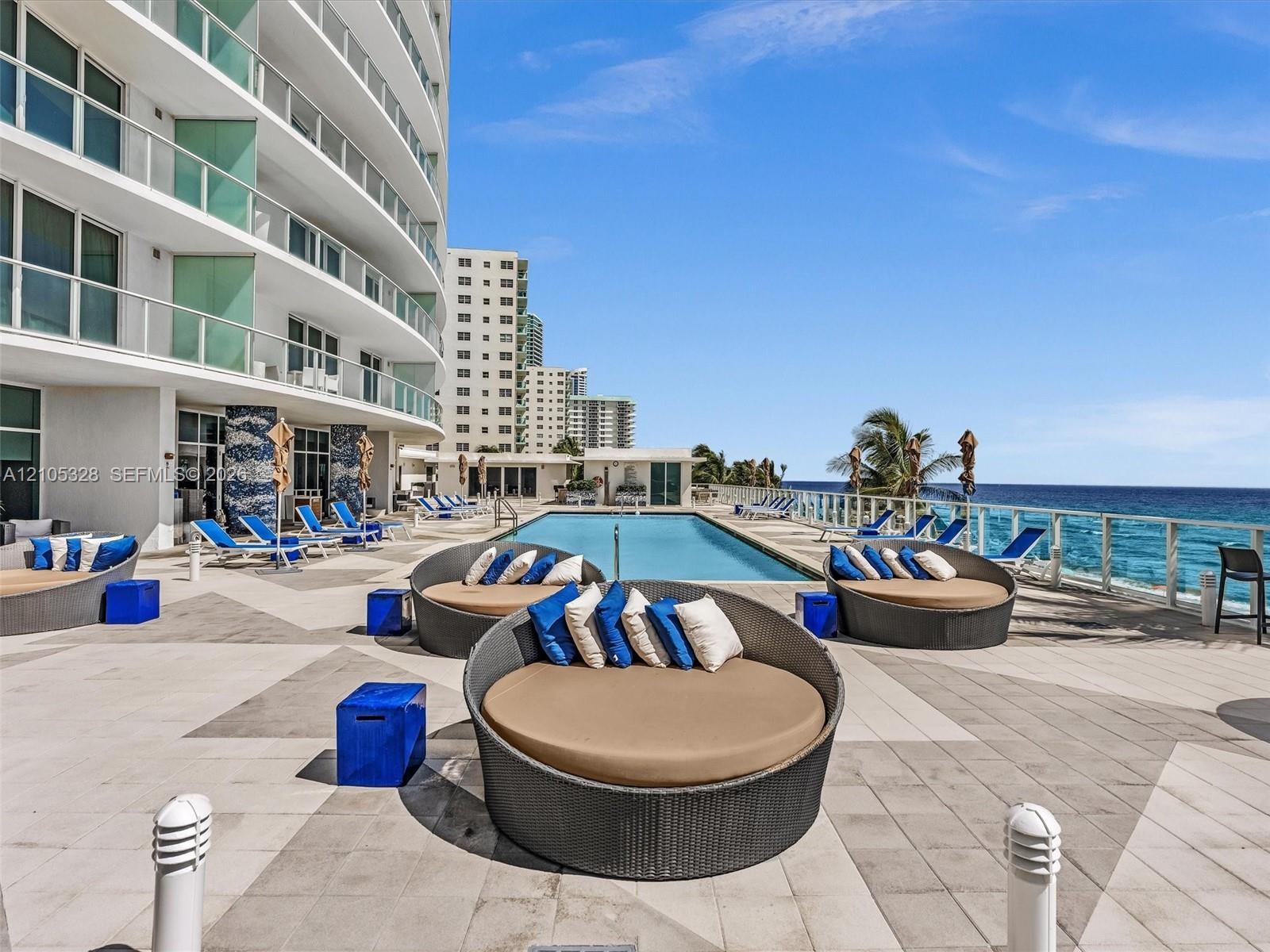 Experience oceanfront resort-style living at Apogee Beach, featuring an inviting swimming pool, expansive pool deck, sleek glass railings, and direct 