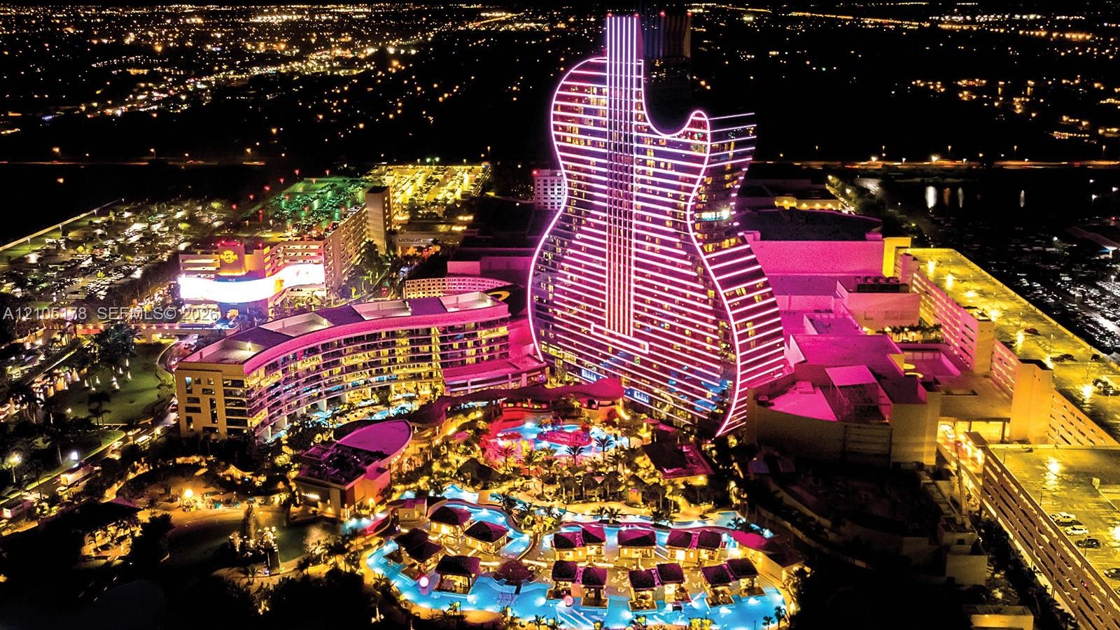 Aerial perspective of a multi-structure complex featuring a guitar-shaped high-rise tower, expansive tiered swimming pools, integrated outdoor hardsca