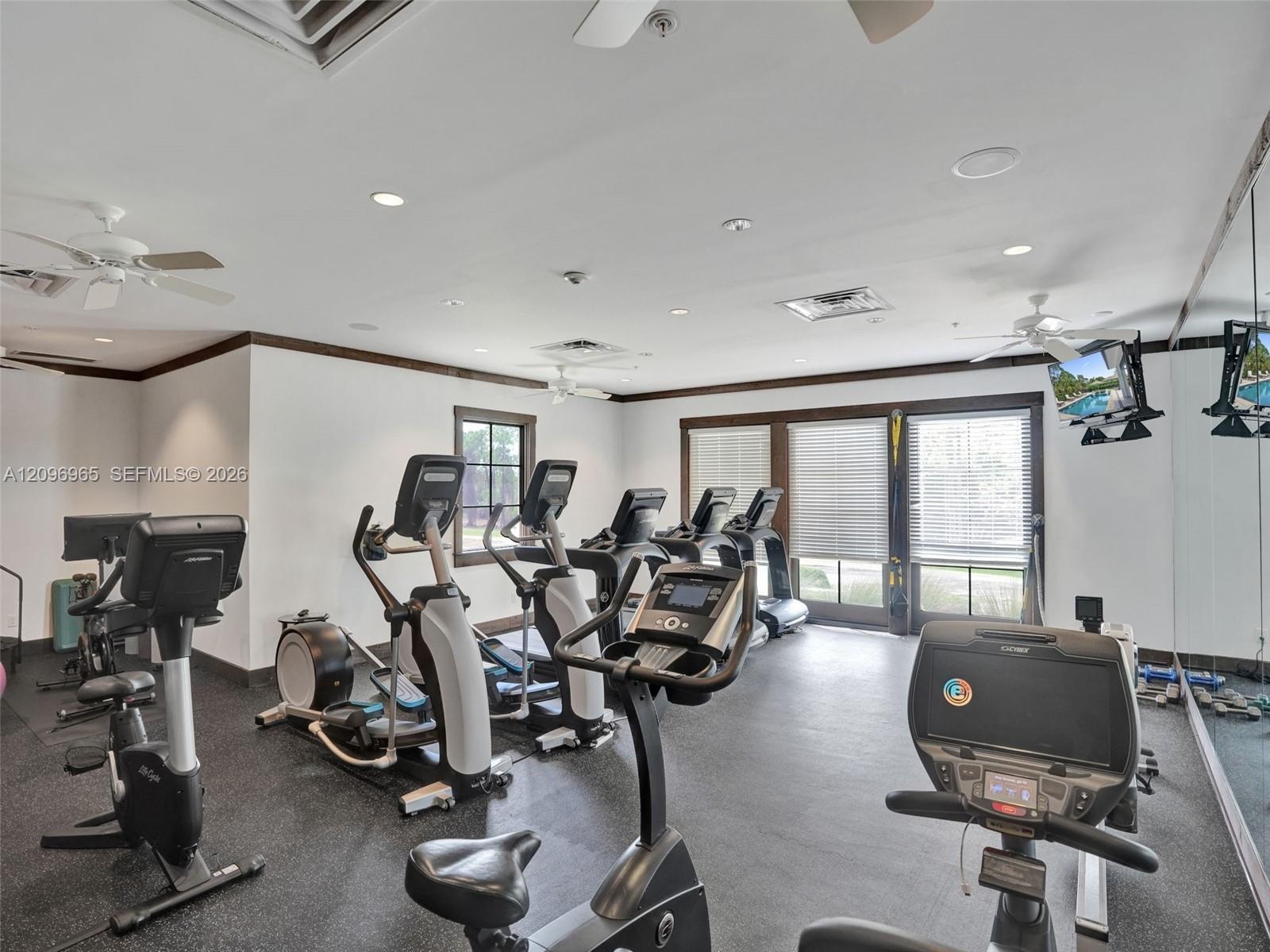 Fitness facility featuring rubberized flooring, mirrored walls, recessed lighting, and expansive windows