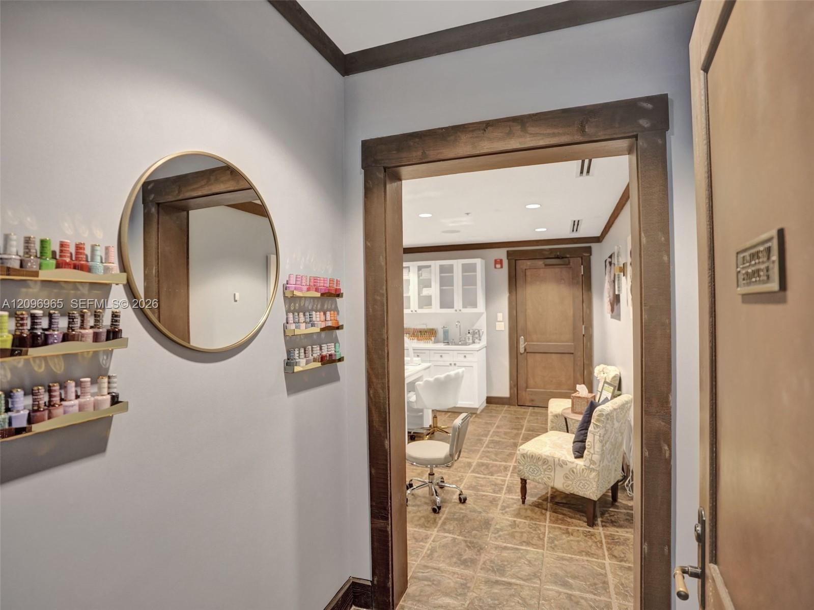 Entry featuring dark-stained wood door trim, crown molding, circular wall-mounted mirror, and stone-finish tile flooring