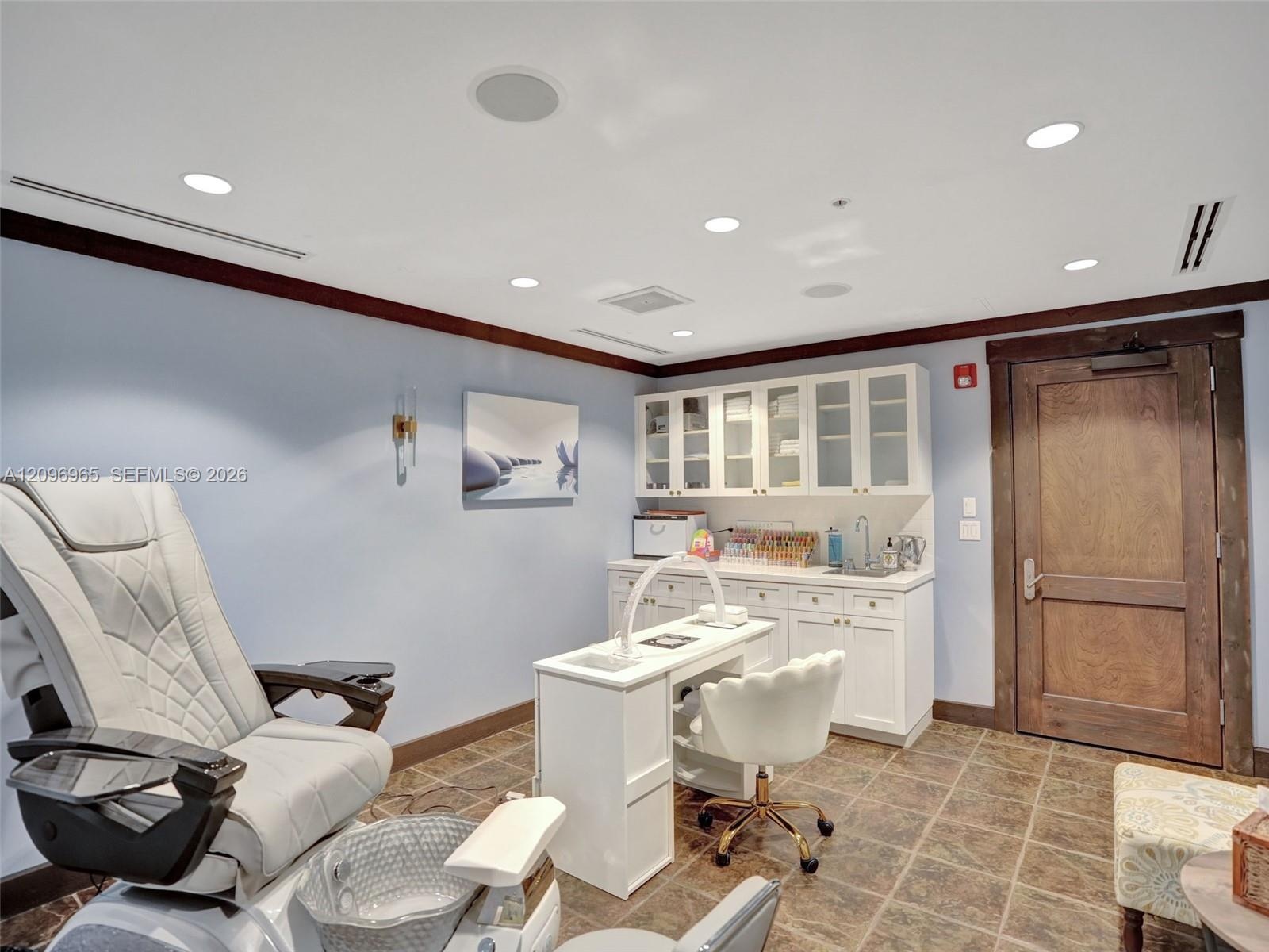 Custom cabinetry featuring glass-front upper doors, stone-finish countertops, integrated sink, recessed lighting, and wood-finish door trim
