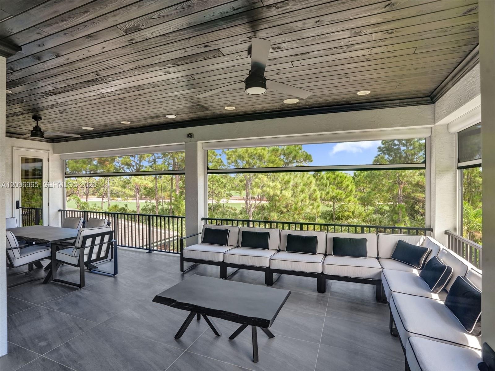 Covered lanai featuring large-format tile flooring, wood-plank ceiling, recessed lighting, ceiling fans, and black metal railings