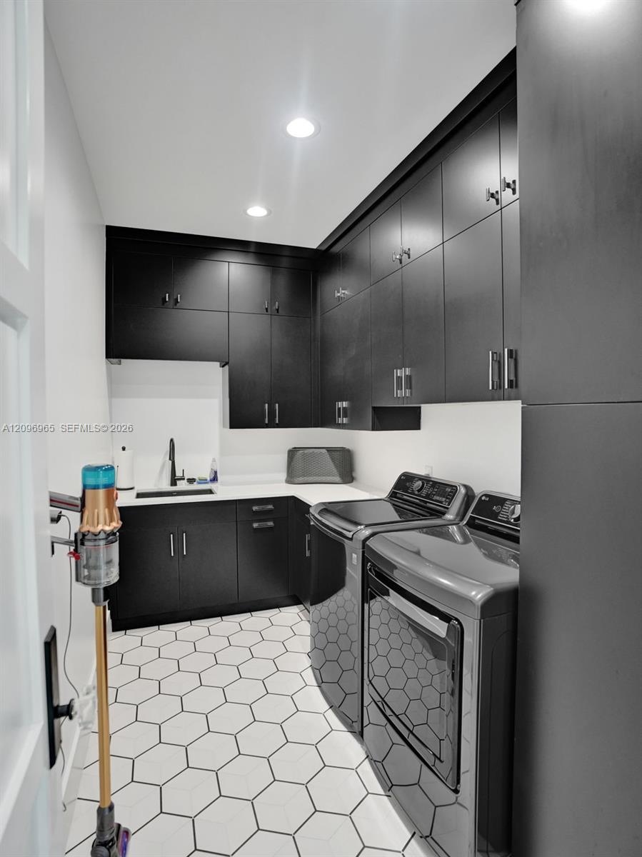 Laundry area featuring full-height matte black cabinetry, contrasting white countertops, an integrated basin with a matte black faucet, and geometric 