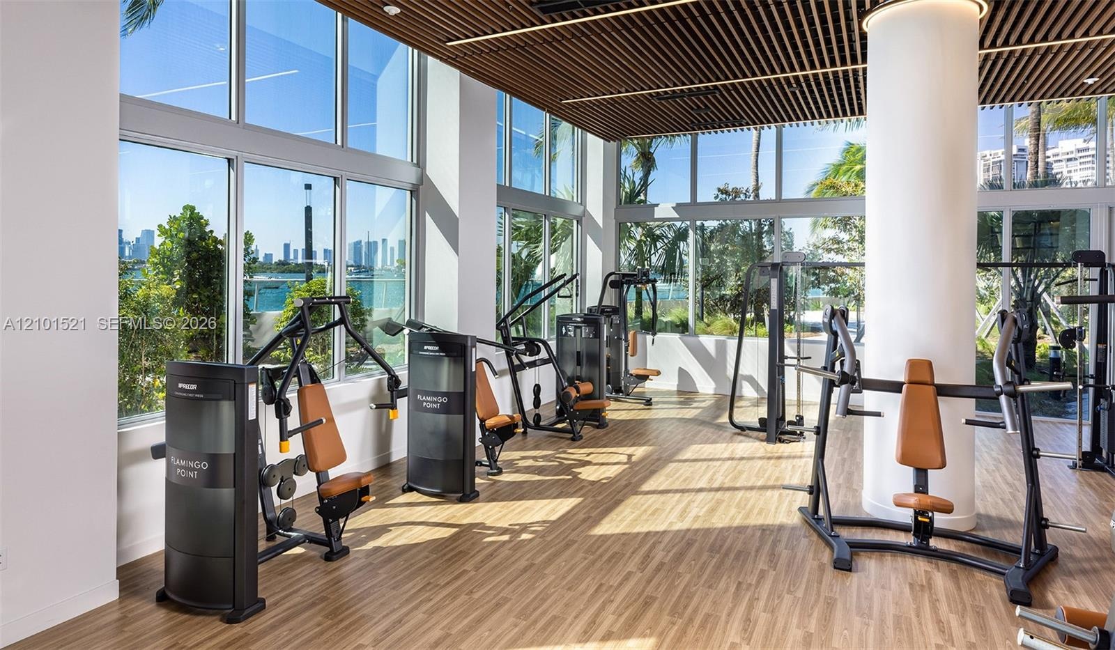 Fitness center featuring floor-to-ceiling windows, wood-finish flooring, linear slat ceiling detail, and integrated lighting