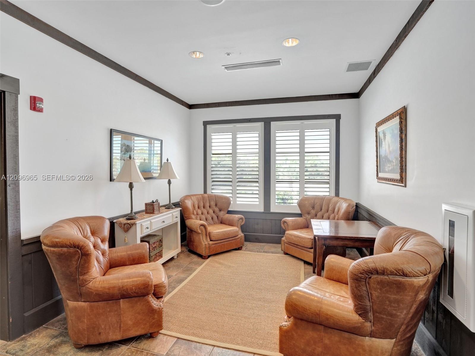 Interior space featuring dark-toned wainscoting, multi-pane windows with integrated shutters, recessed ceiling lighting, and stone-finish flooring