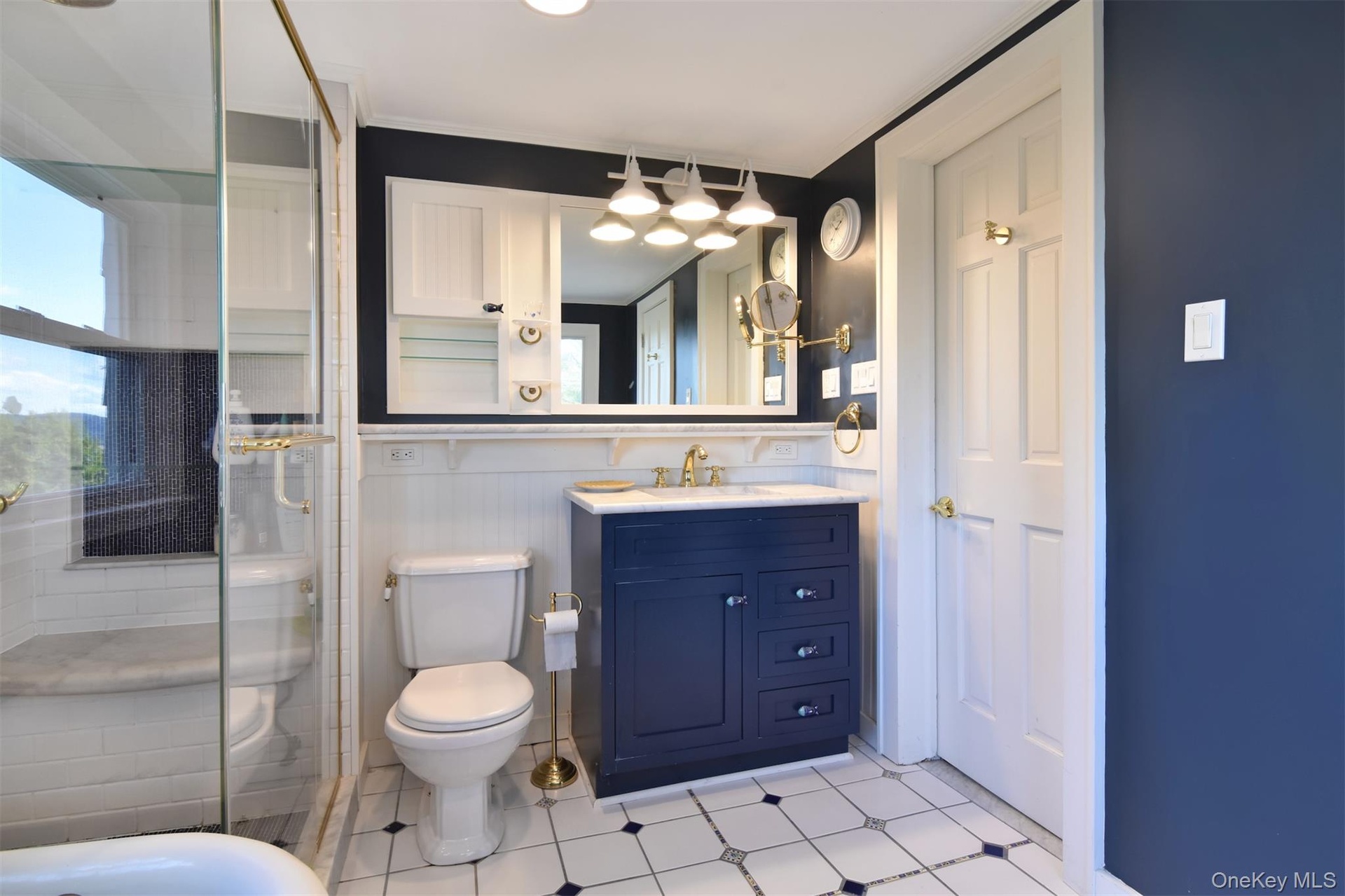 Tiled bath with glass-enclosed shower.