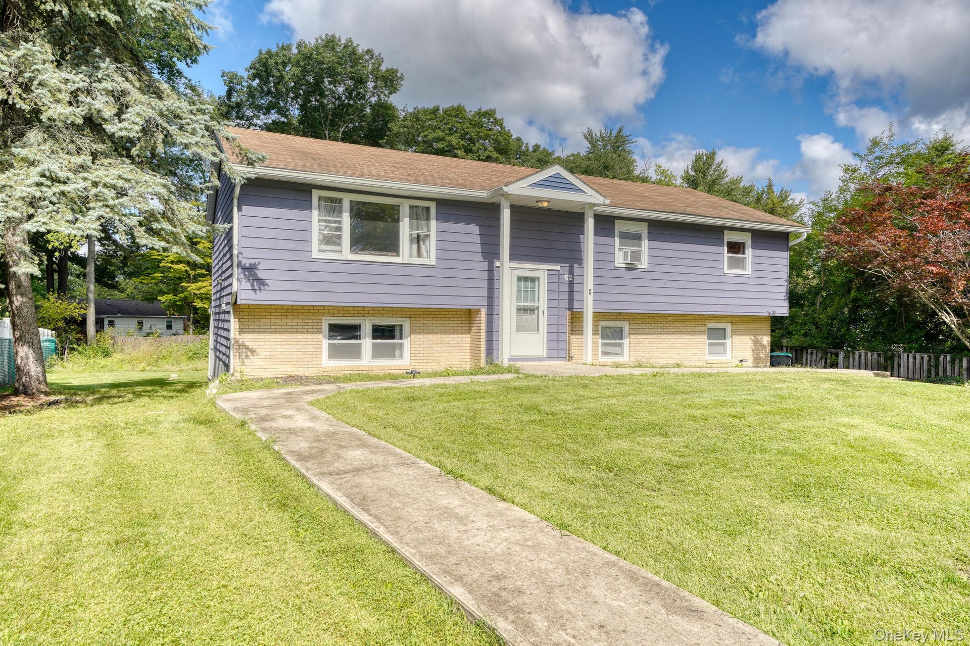 Beautiful split-level home with a welcoming front entrance and manicured lawn. The exterior features a unique combination of soft purple siding and li