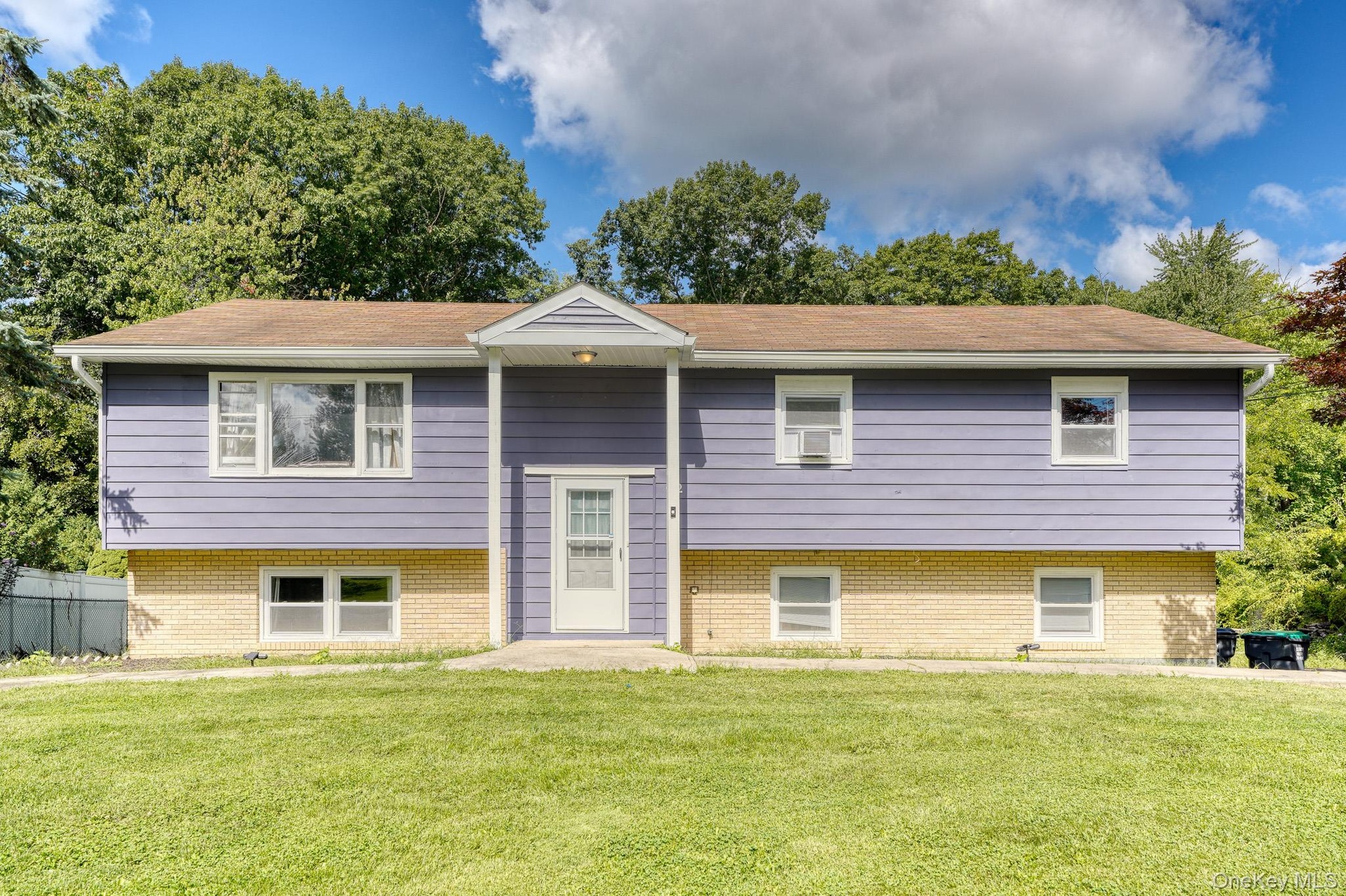 Charming two-story split-level residence showcasing a clean, modern look with purple siding and light brick accents. The symmetrical façade includes m