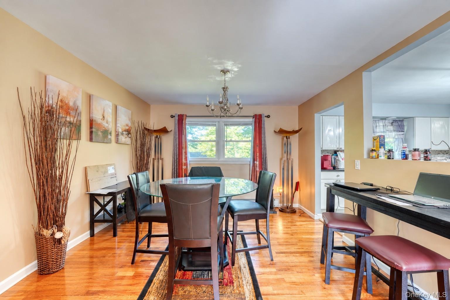 Warm and inviting dining area featuring hardwood floors, neutral walls, and a modern glass-top table with four leather chairs. Natural light pours in 